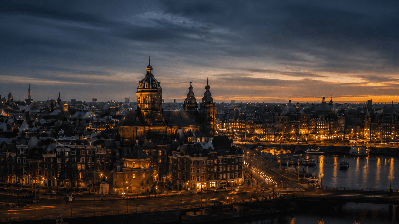 Amsterdam at dusk seen from above, church domes and lit streets along the water