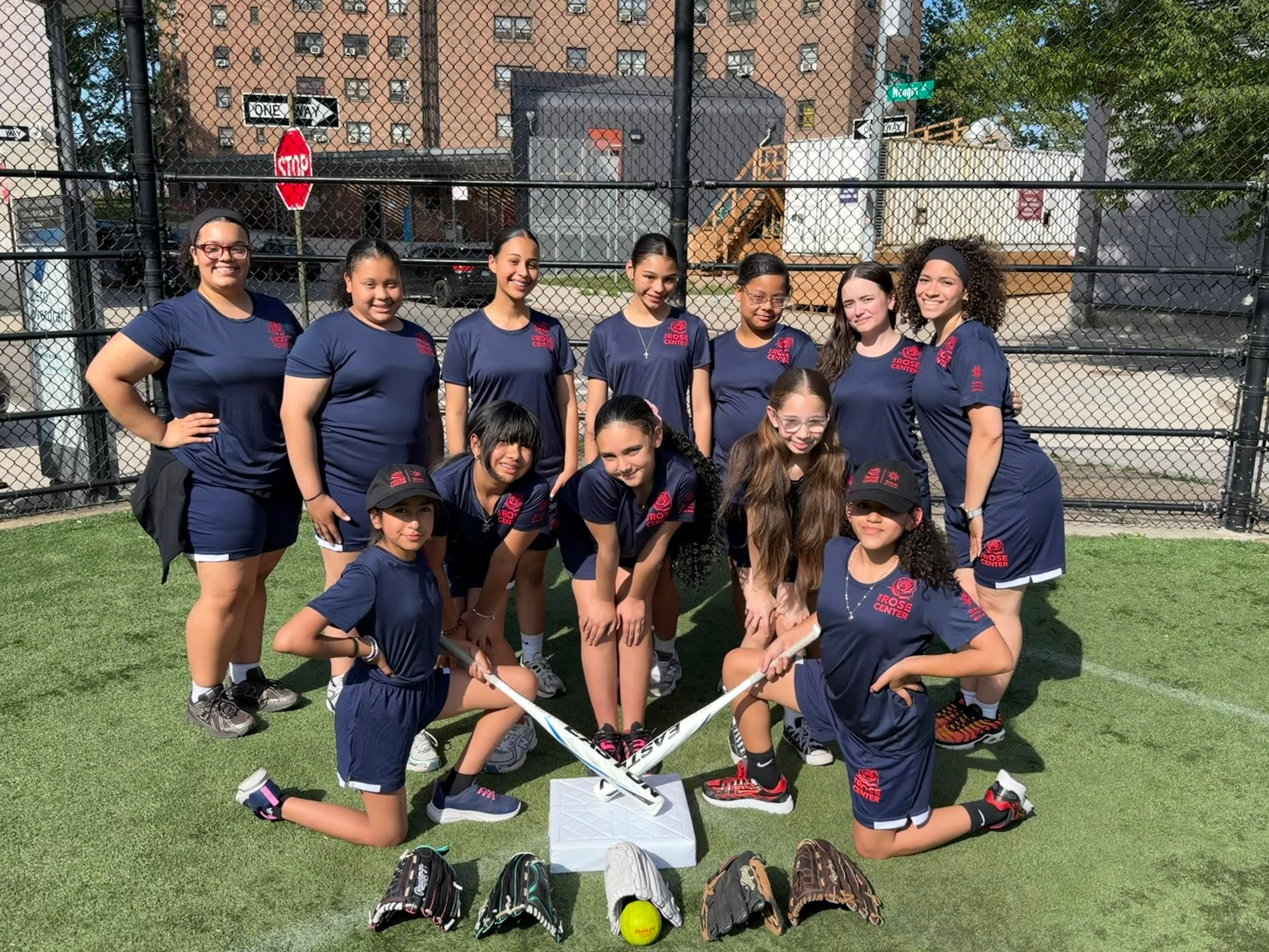 A girl's softball team poses showing off their uniforms and gear.