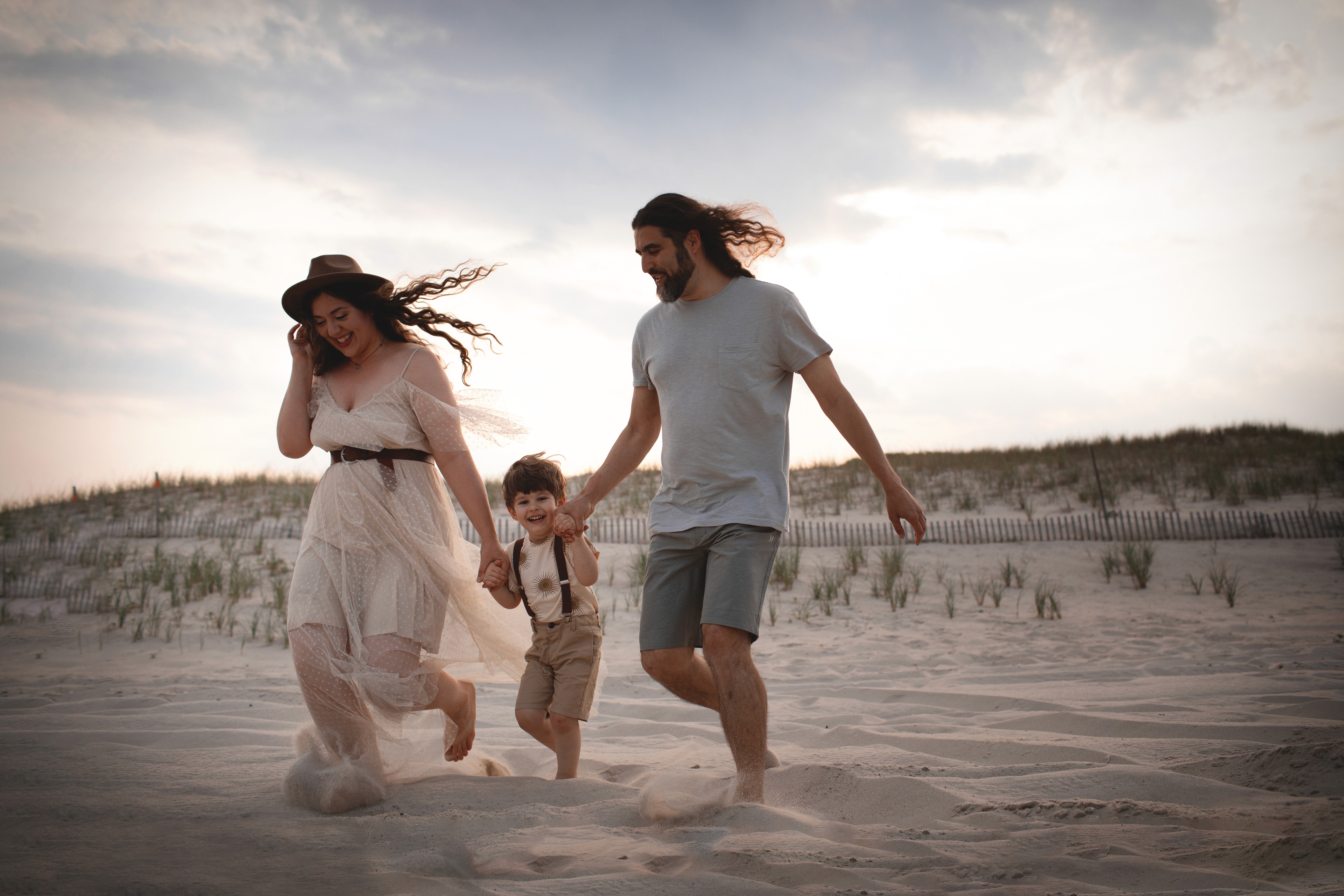 Parents walking with their child near the ocean pier during a relaxed lifestyle family session.