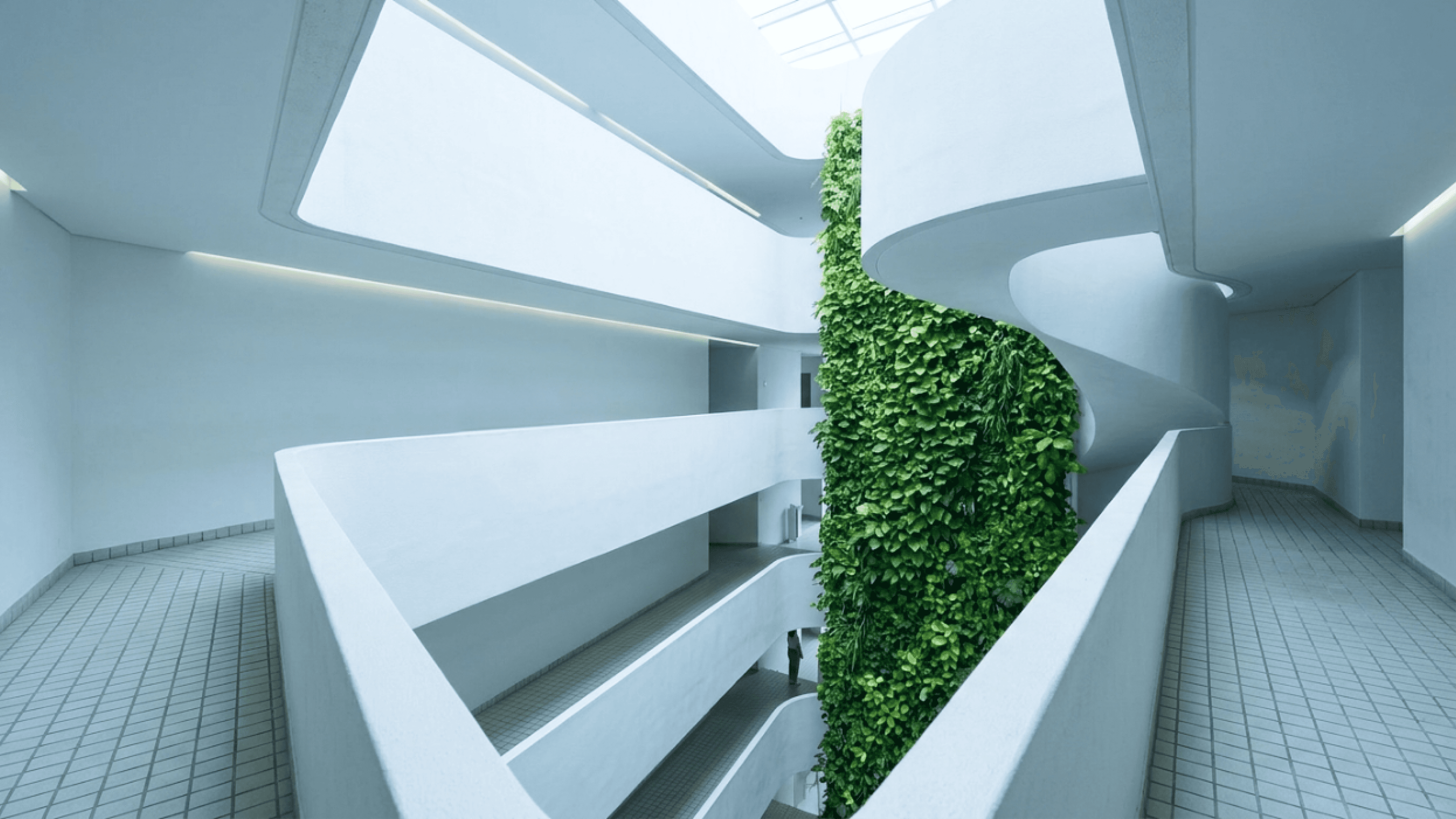 Minimalist white interior with curved balconies and a lush vertical garden column spanning several floors.