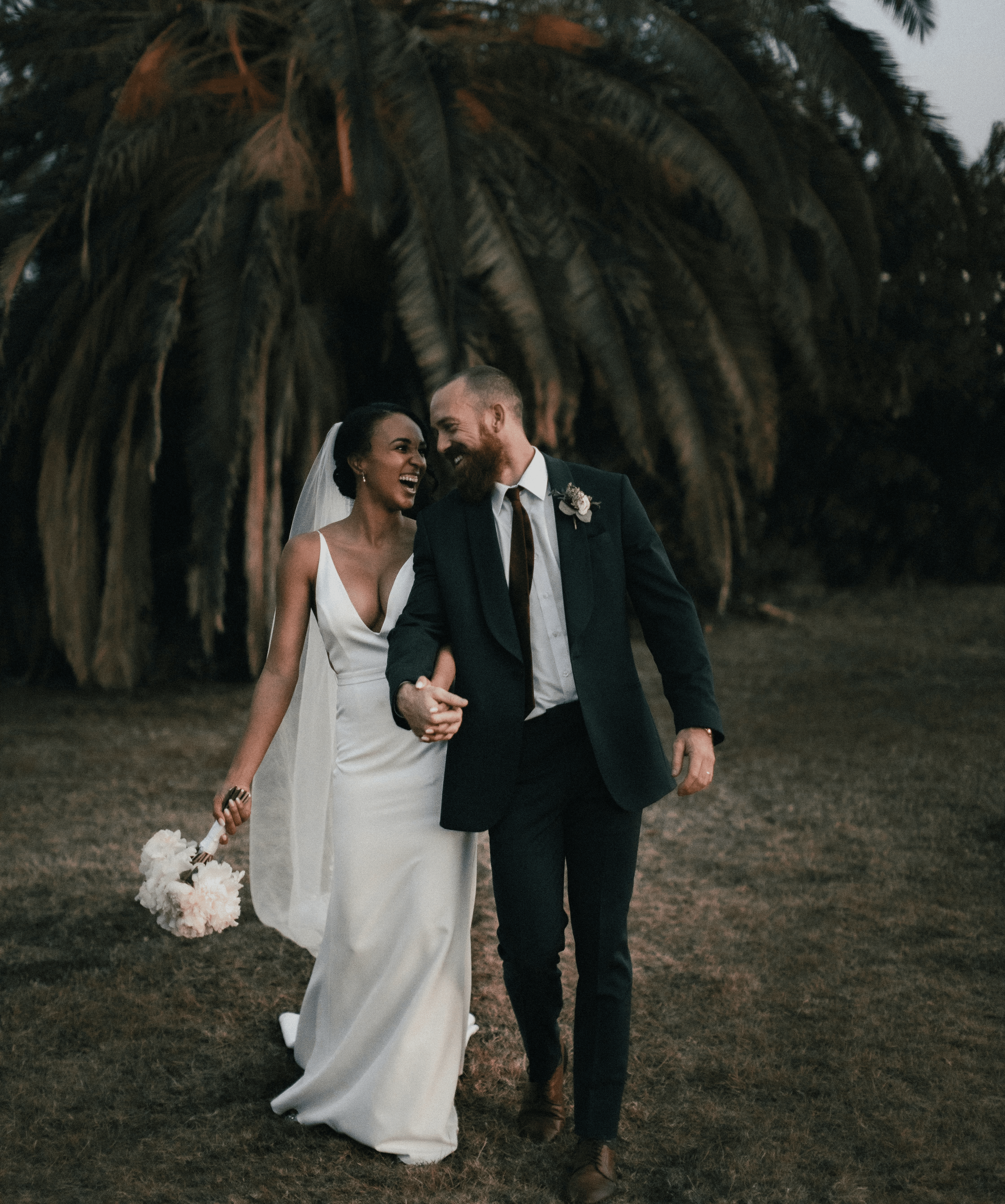 a newly married couple walking through a field