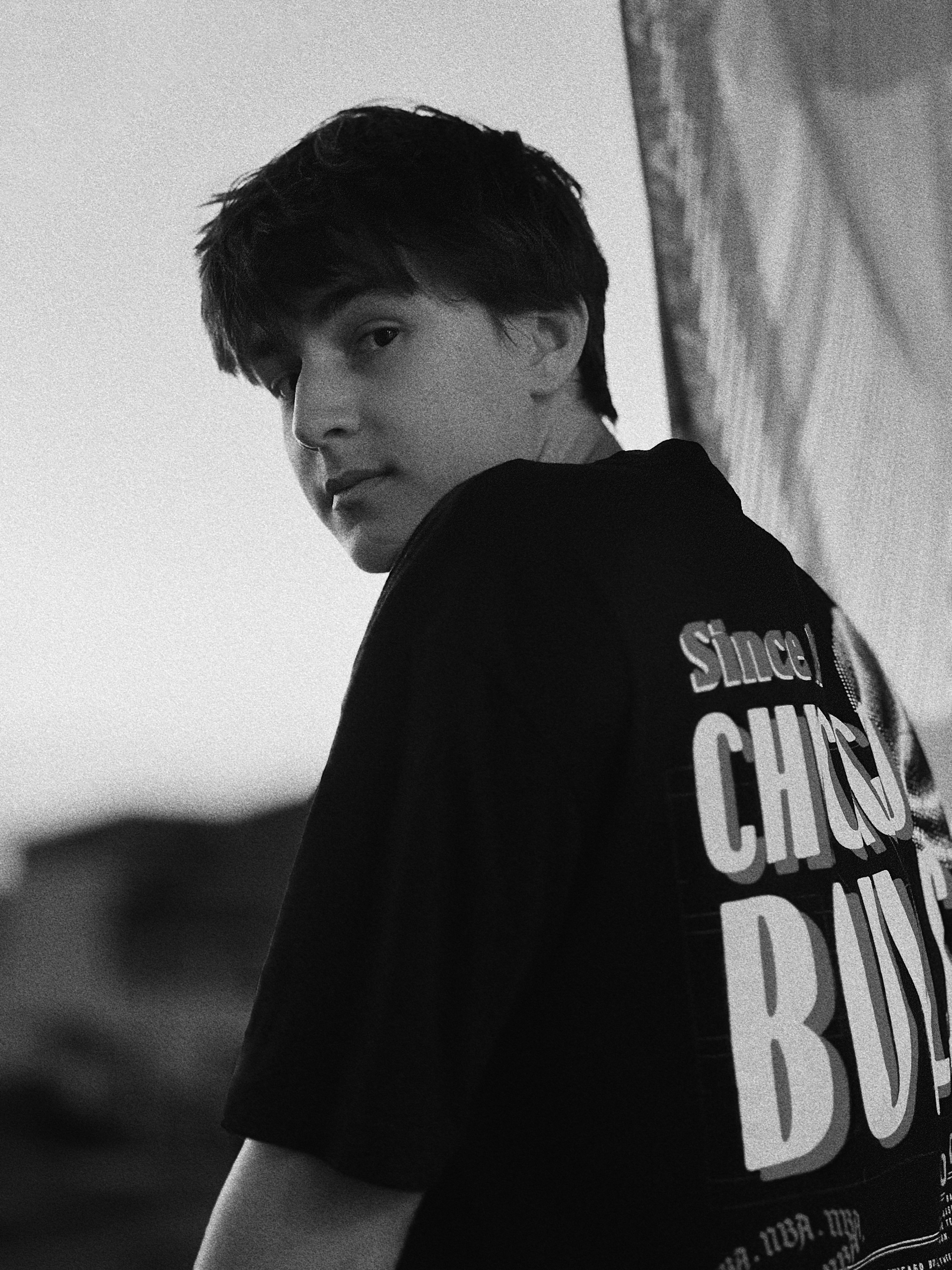 A young man holding a skateboard next to a fence
