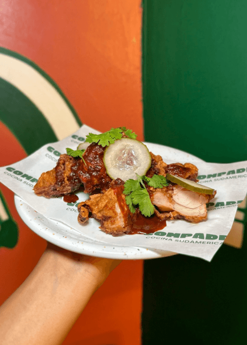 Poulet frit façon street food latino avec sauce épicée, pickles et coriandre fraîche, servi au restaurant Compadre, cuisine sud-américaine à Paris