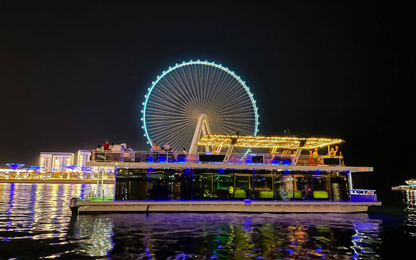 Hausboottour auf Ain Dubai mit beleuchtetem Riesenrad im Hintergrund.