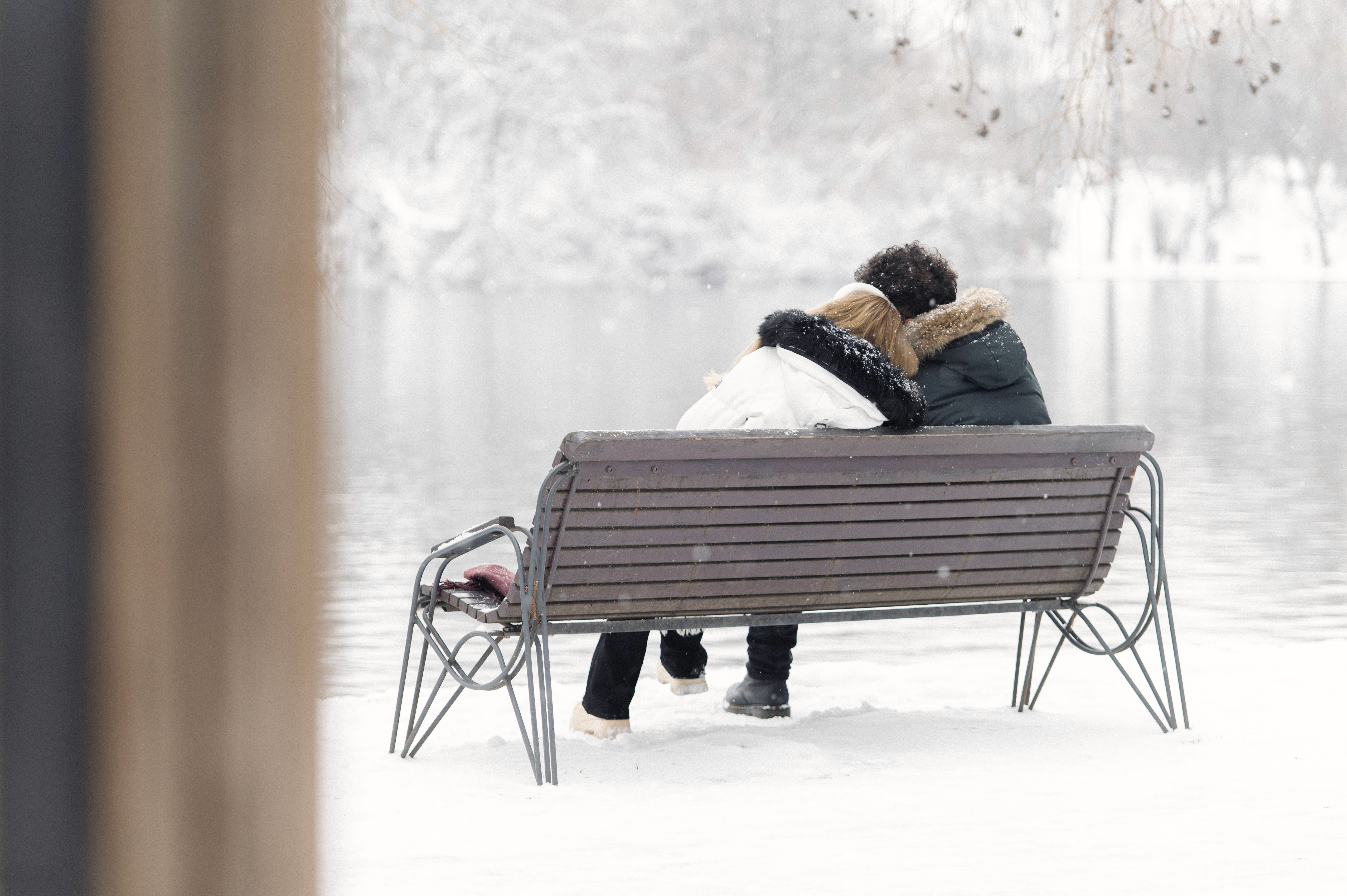 Cadru artistic Save the Date cu un cuplu în parc iarna, fotografiat într-un peisaj minimalist cu zăpadă