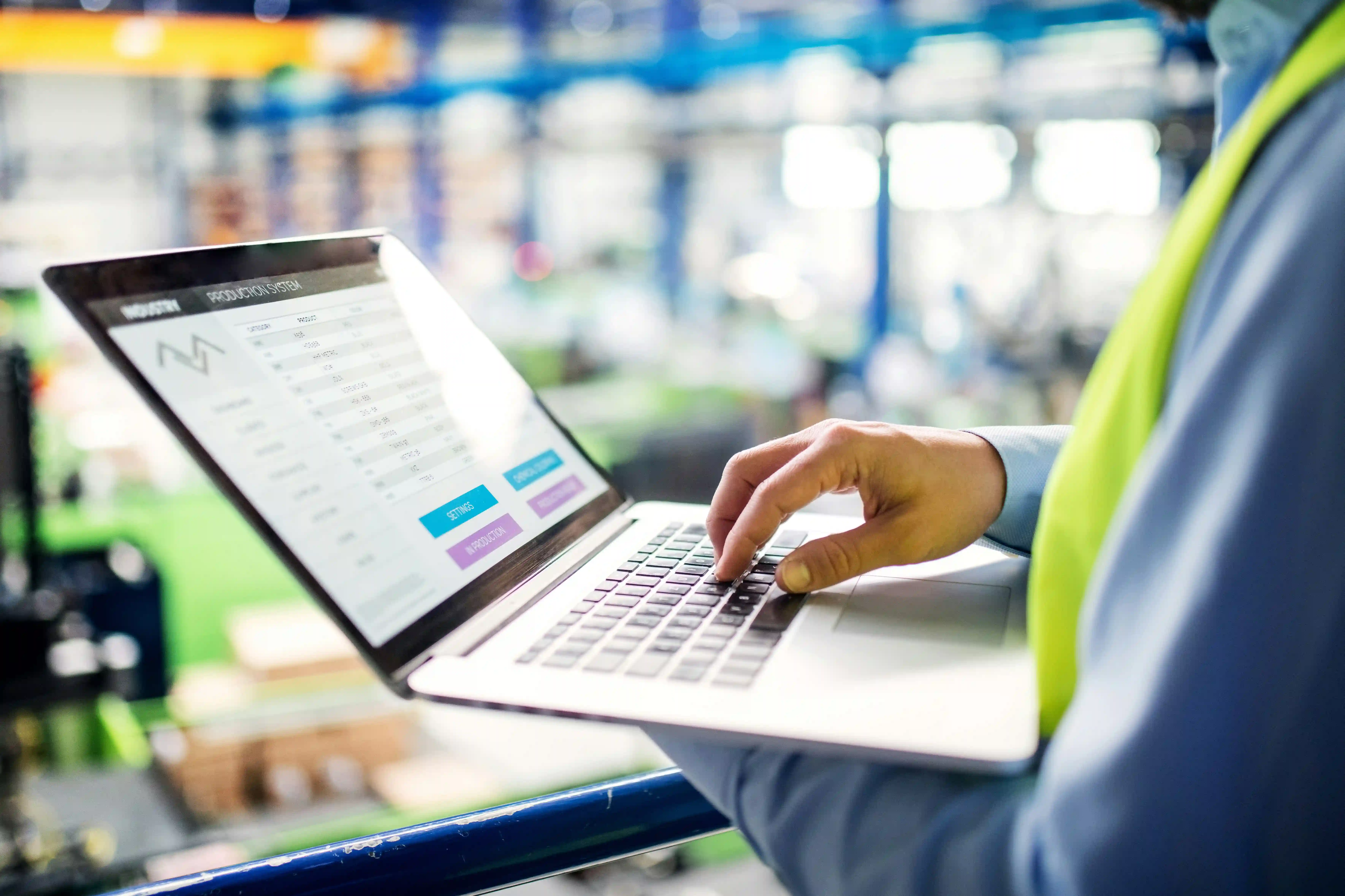 close-up of a warehouse worker using a WMS system on a laptop