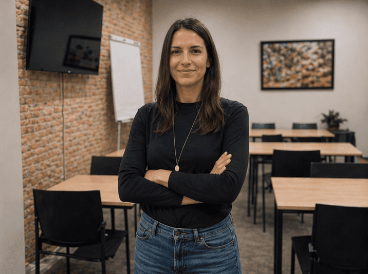 Dos mujeres jóvenes estudiando juntas en una mesa iluminada por luz natural. Una de ellas escribe mientras la otra observa con atención, creando un ambiente de colaboración y aprendizaje.