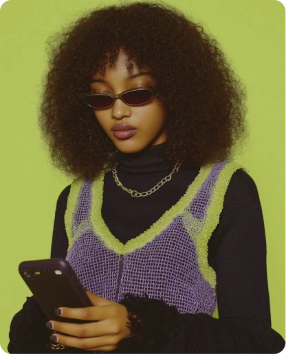 A stylish young woman with an afro hairstyle and sunglasses looking at her smartphone against a vibrant lime green background