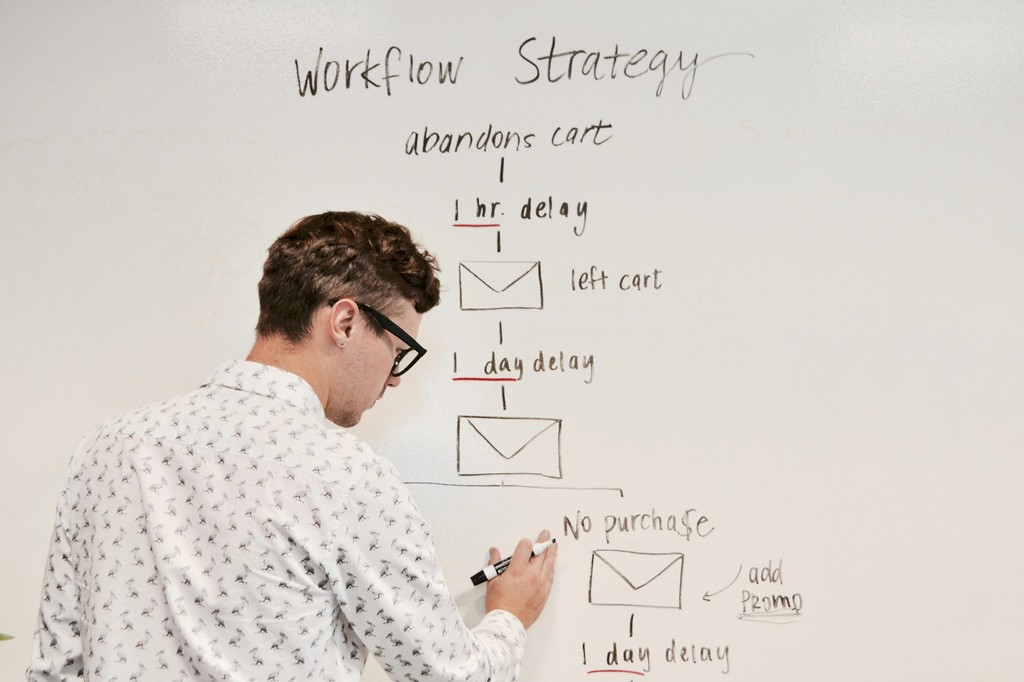 A young man is creating a workflow on a white board for Airtable.