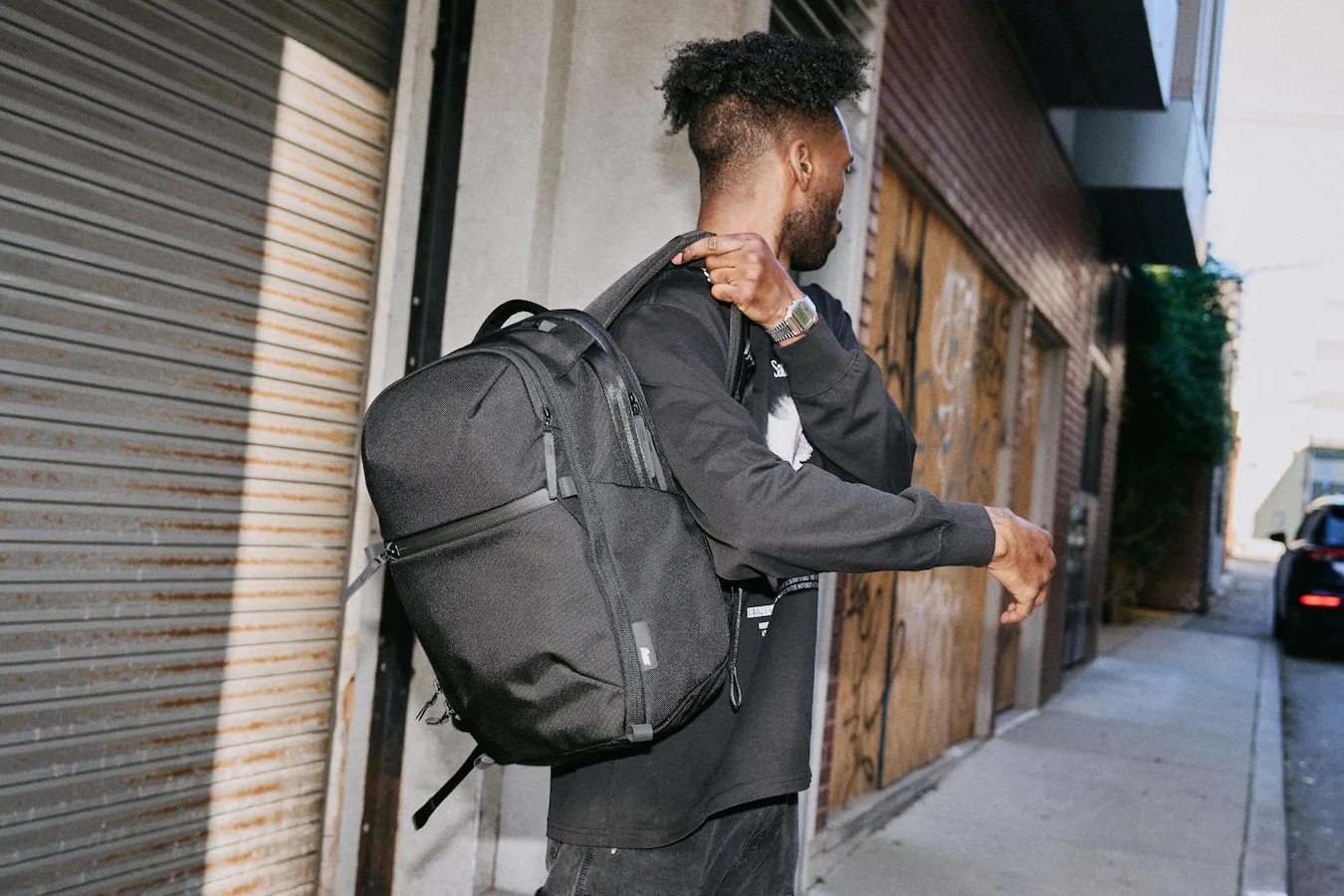 Man carrying black backpack walking through city