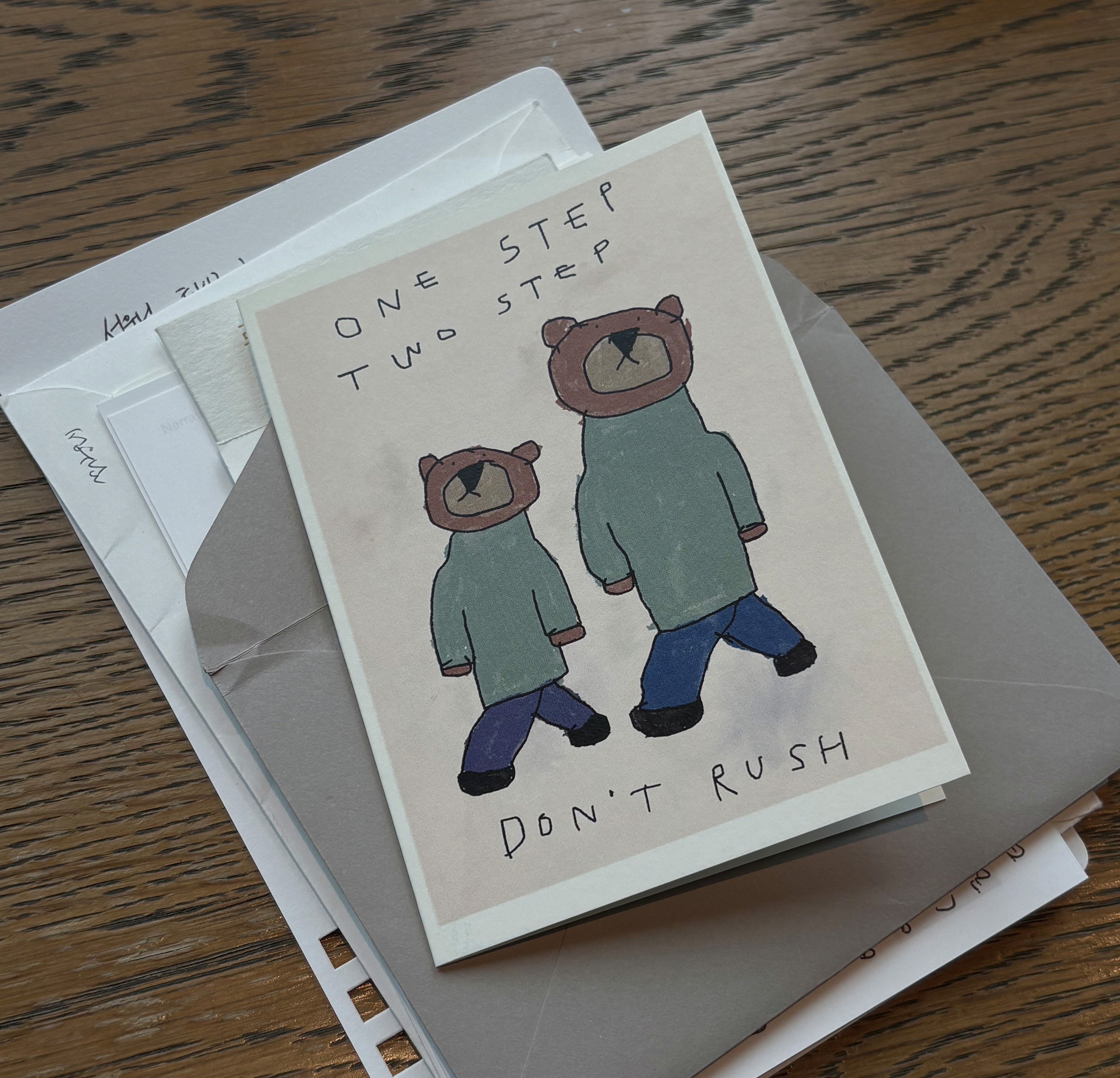 곰 두 마리가 나란히 걷는 그림과 ONE STEP TWO STEP DON'T RUSH 문구가 적힌 카드, 그 아래 편지 봉투들