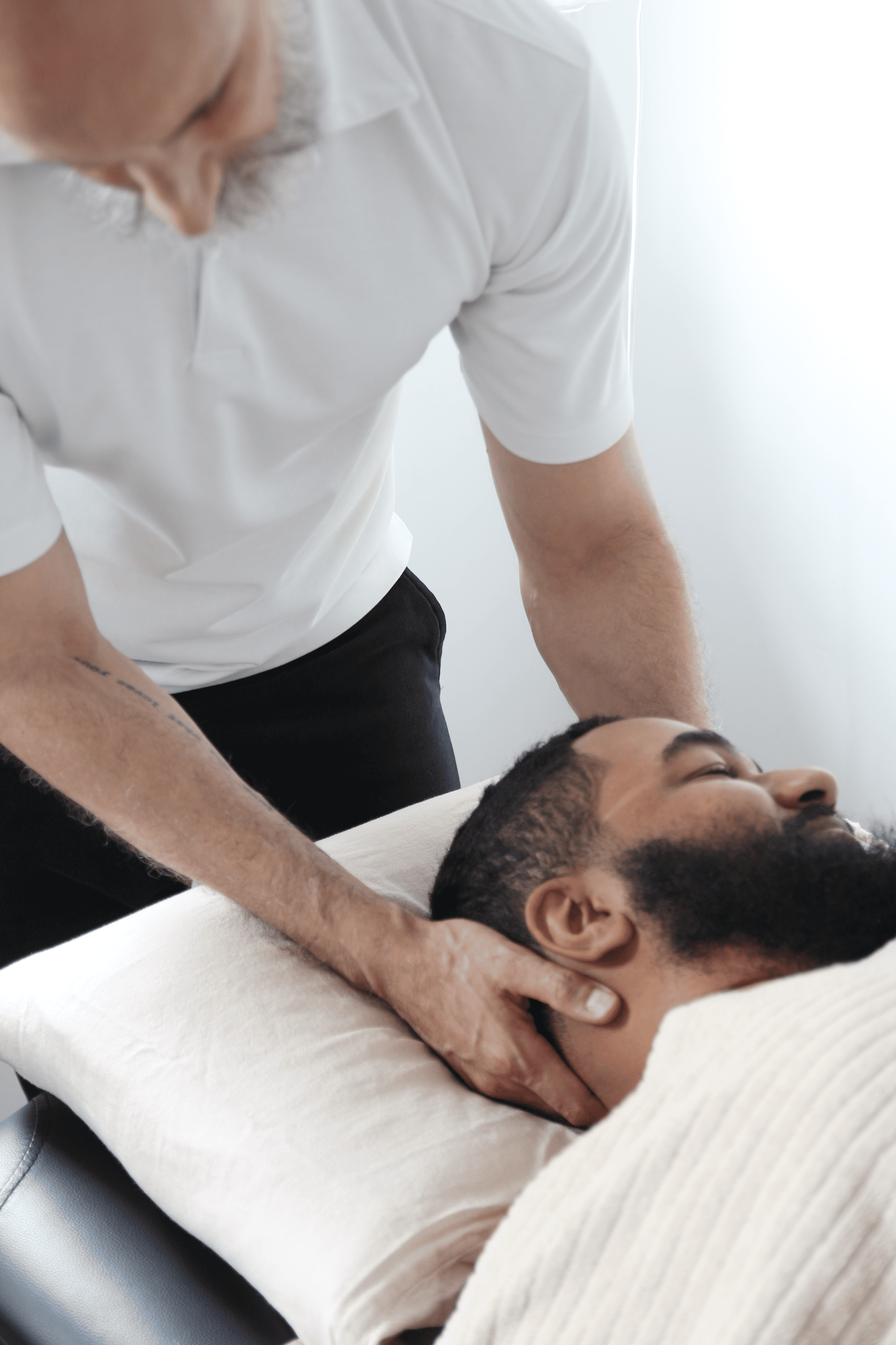 Close-up portrait of a young woman with green eyes, natural makeup, and dark hair, gently touching her face, against a neutral beige background