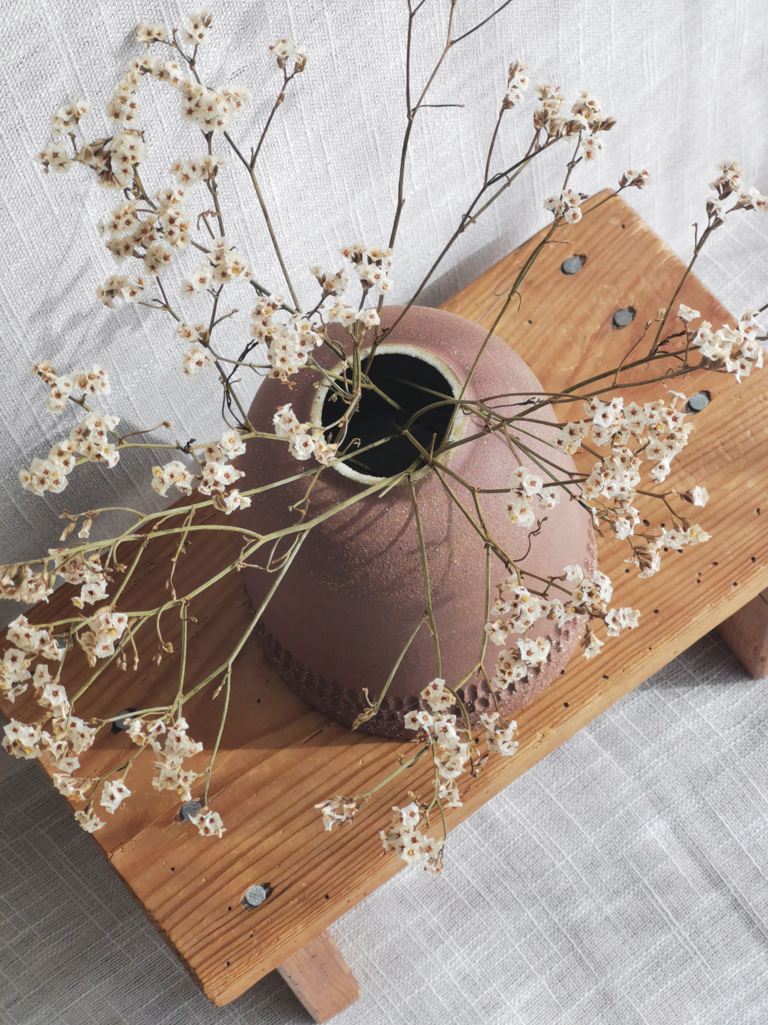Vase sphérique en grès rose à motifs gravés entouré de fleurs séchées – céramique artisanale Guérande