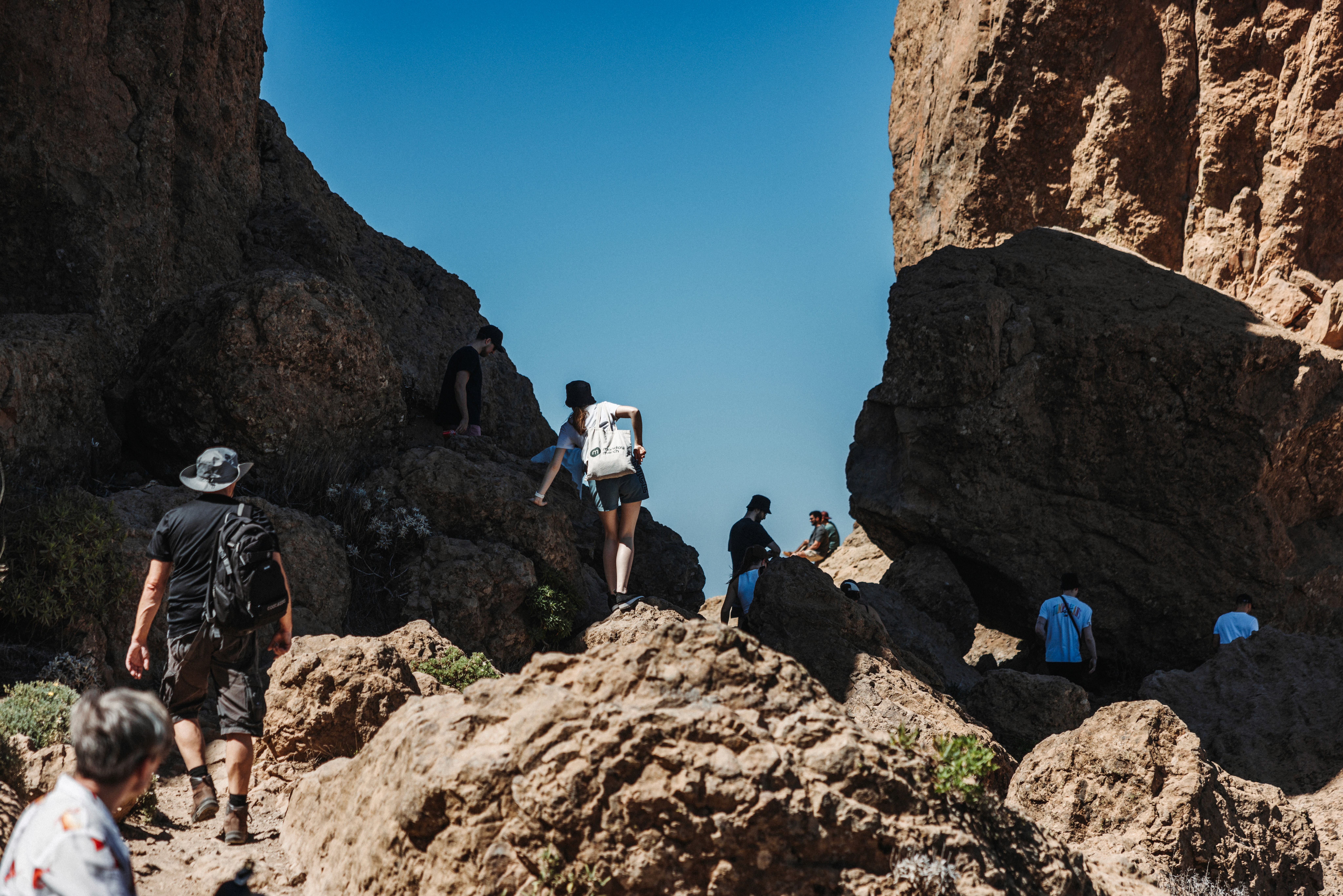 People hiking through rocky terrain under a clear blue sky