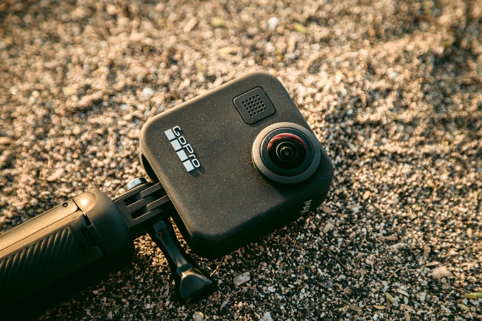 A GoPro camera with a 360-degree lens lying on sandy ground, used for creating VR videos.