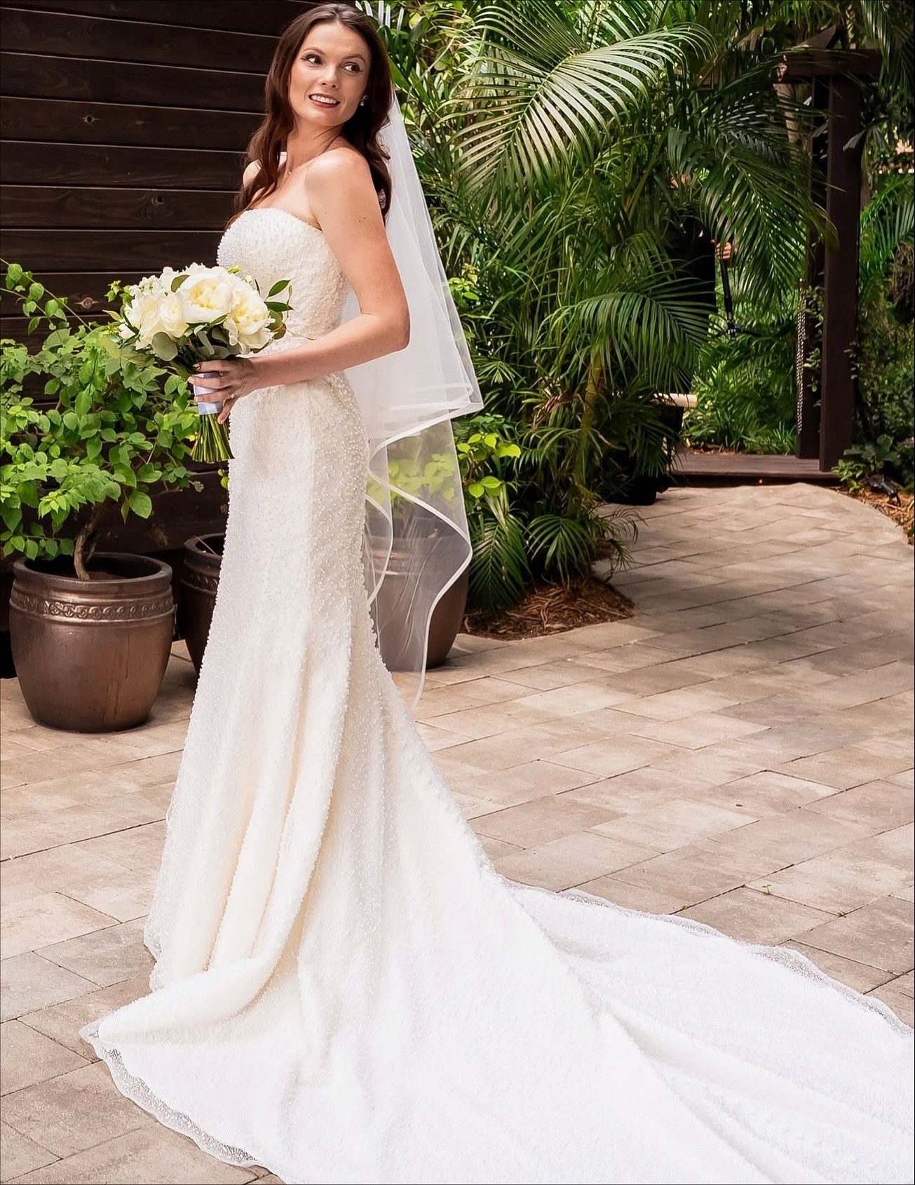 A woman lying down with a towel wrapped around her head, her face glowing with facial oil. She has a peaceful expression, enjoying a skincare treatment.