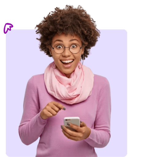 A woman with curly hair and glasses, wearing a pink scarf and sweater, looks surprised and points at her smartphone against a light purple background.