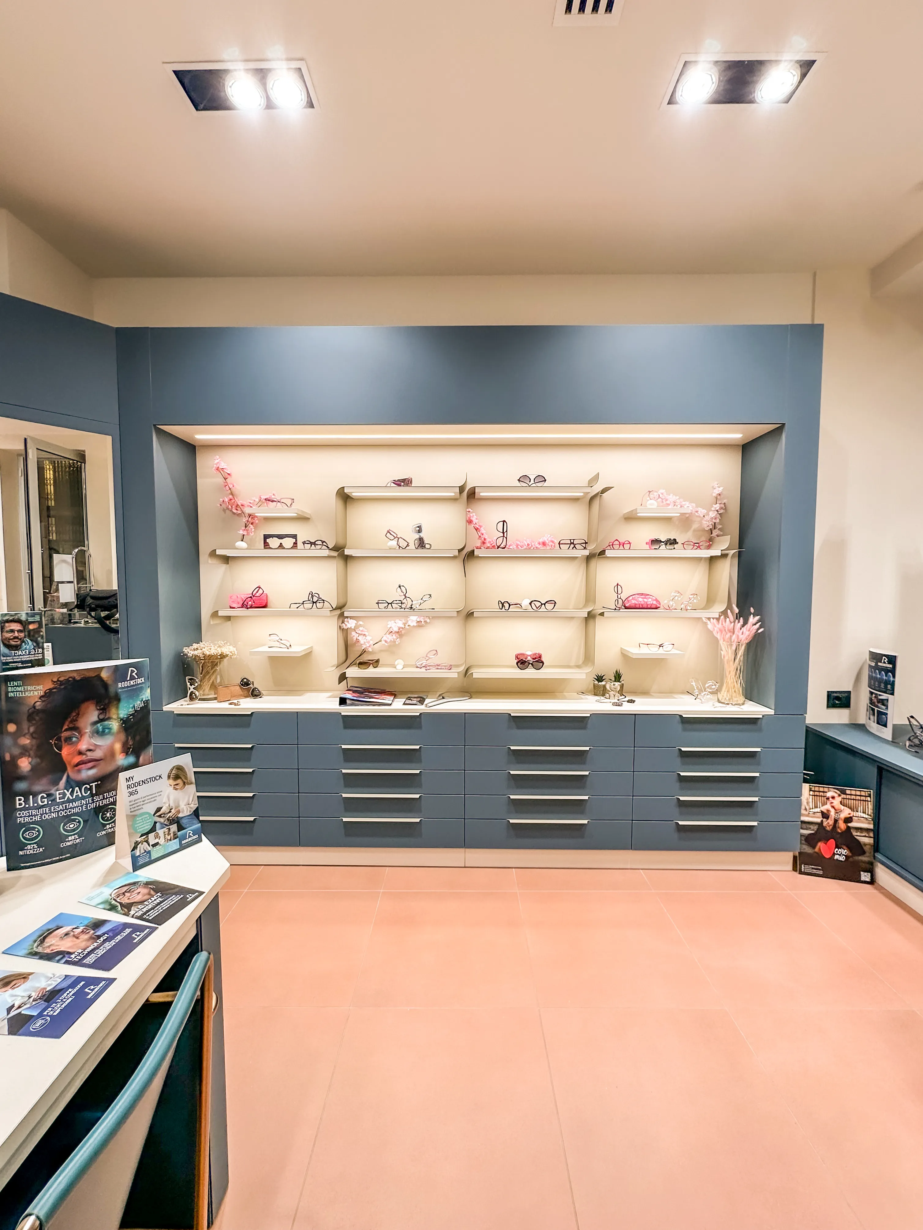 Interno del punto vendita Ottica Dentella ad Ancona con esposizione di occhiali da vista e da sole su scaffali illuminati, utilizzato come immagine di apertura della pagina Prodotti. La fotografia introduce la selezione di montature, lenti e soluzioni ottiche proposte da Ottica Dentella, con particolare attenzione a eyewear indipendente e artigianale, design, qualità dei materiali, comfort visivo e personalizzazione della scelta dell’occhiale in base alle esigenze della persona.