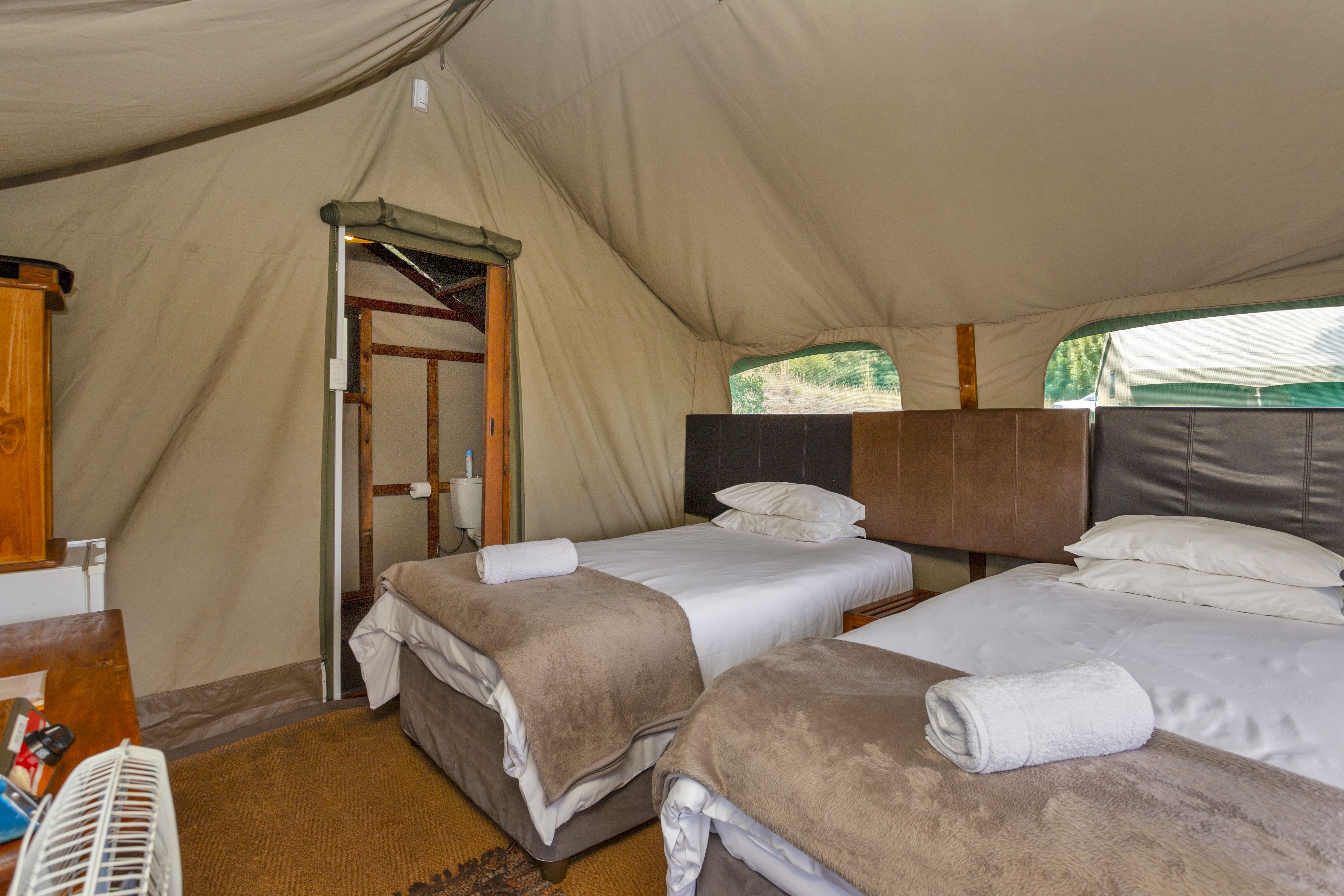 Kilimanjaro Elephant Ride, Arusha, Tanzania. En kvinna sitter och läser utanför ett tält uppsatt i vildmarken.