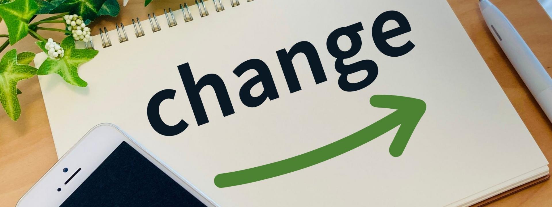 ノートに「change」と書かれた文字と緑の矢印、植物とスマートフォンが周囲に配置された画像