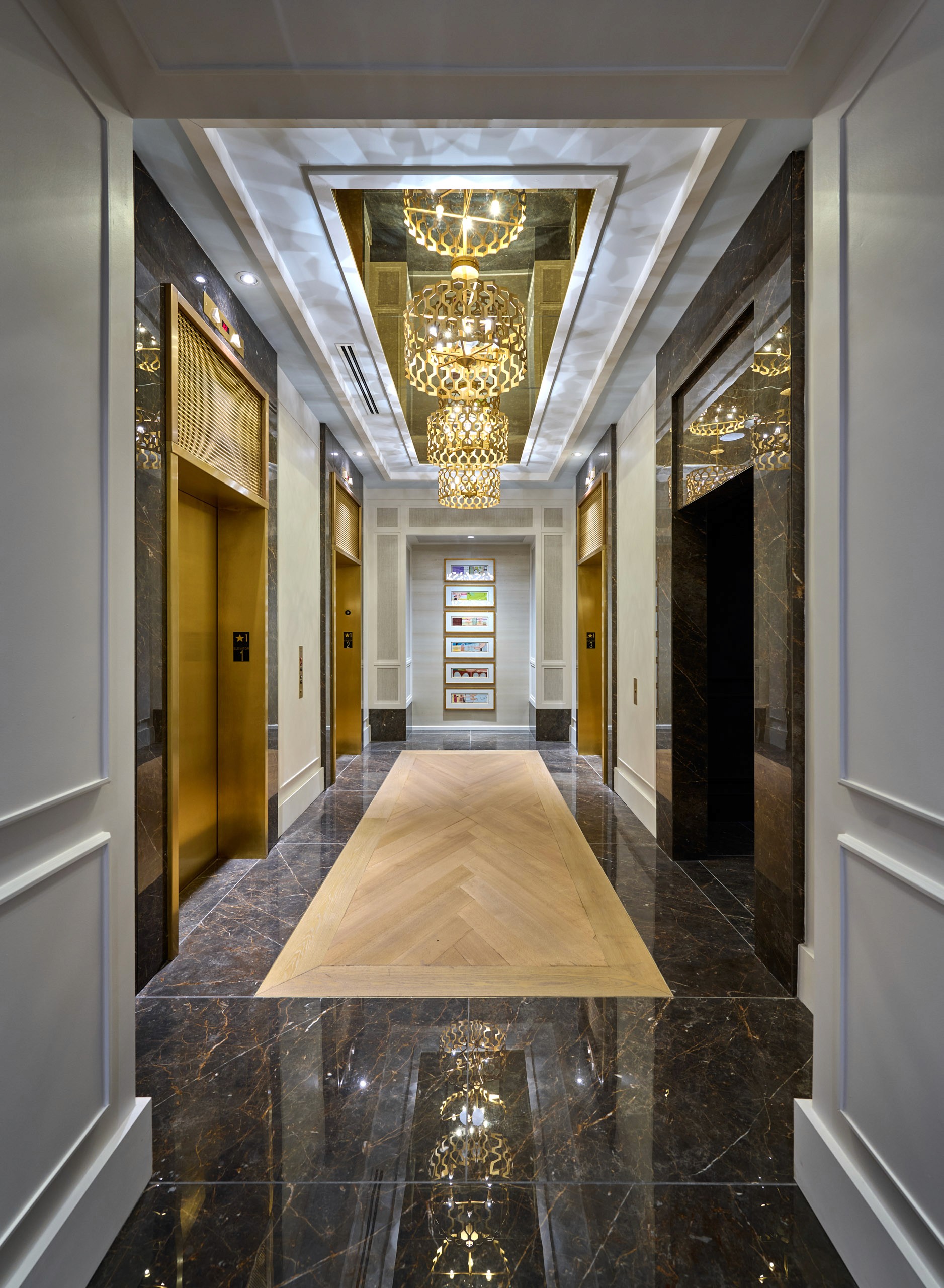 Luxury hotel hallway with gold elevators and ornate chandeliers