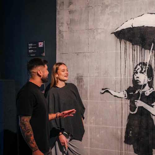 Para rozmawiająca przed dziełem sztuki Banksy'ego.