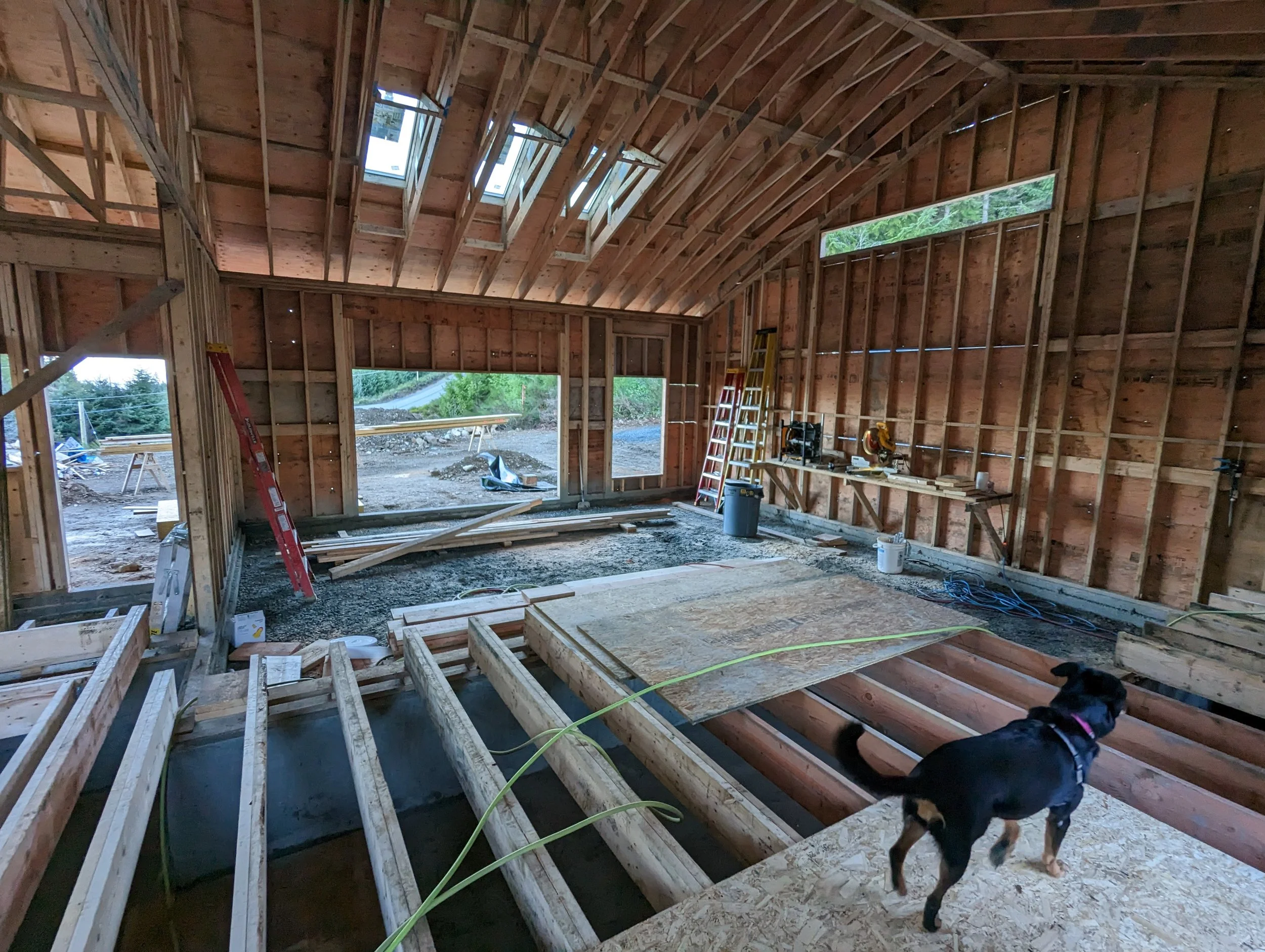 Modern two-story home with large glass windows, warmly lit interiors, and a balcony. Surrounded by trees and a manicured lawn at dusk. Cozy ambiance.