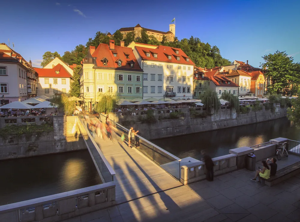 Evening sunlight on Ribja brv bidge in Ljubljana city center, with Ljubljana castle watching over the city from the hill above.