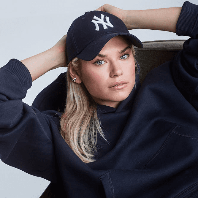 Woman wearing navy blue Sunday Superior Hoodie whilst laying in a dark green sofa