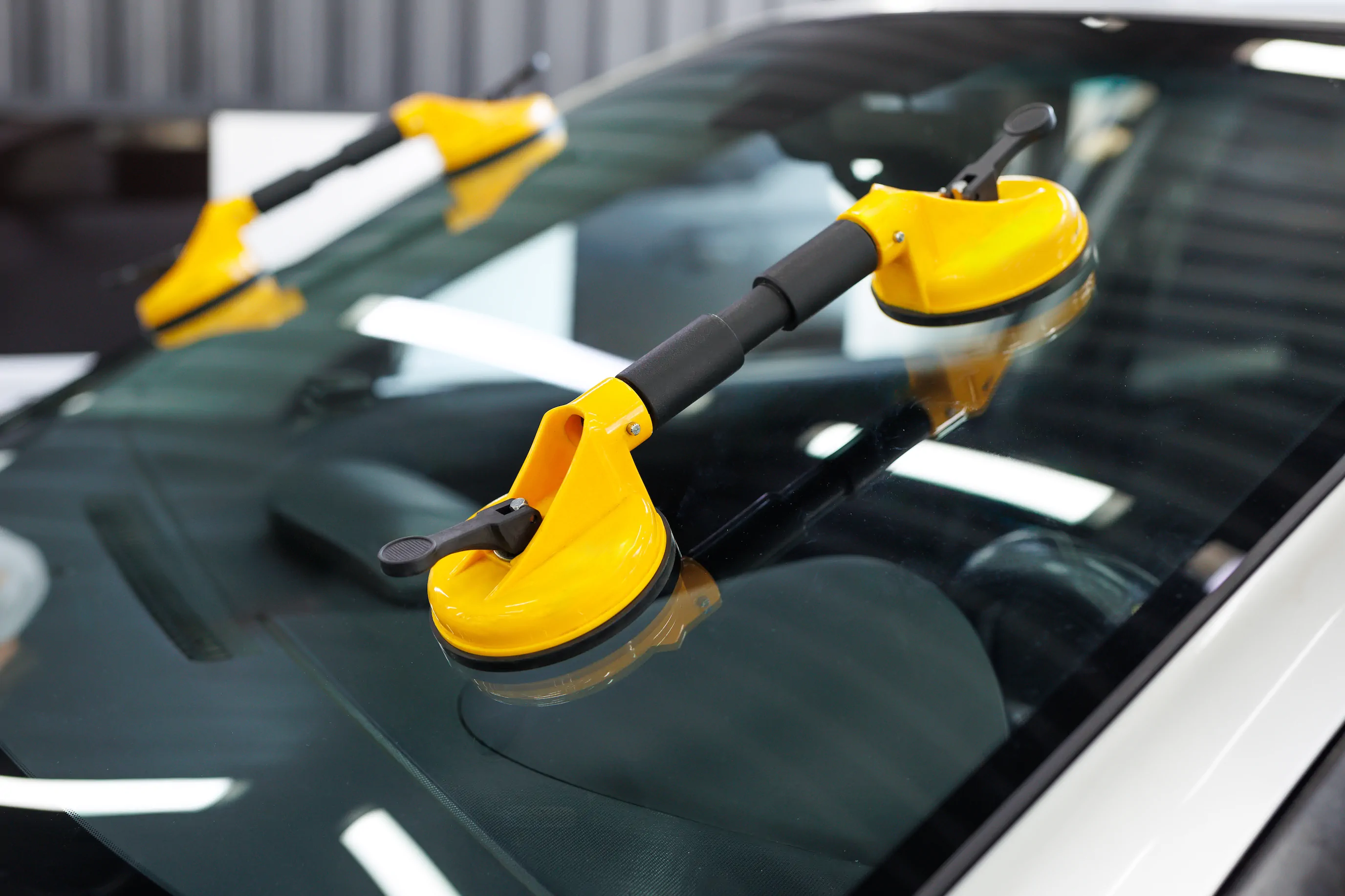 Gros plan sur une voiture avec ventouses jaunes fixées sur le pare-brise pour la réparation de la vitre.