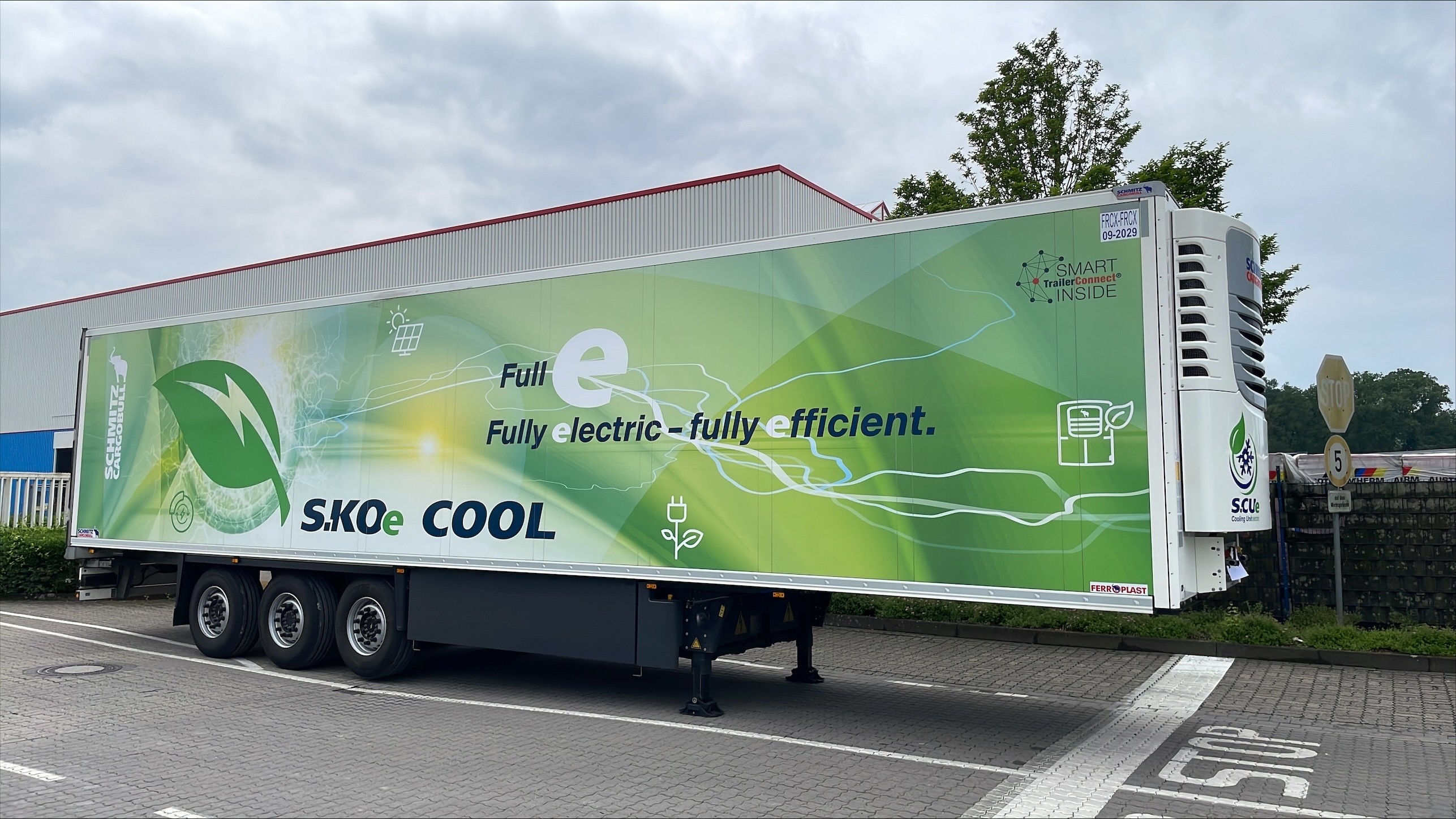 The all-electric Schmitz Cargobull S.KOe COOL trailer parked at a facility, illustrating its role in sustainable logistics.