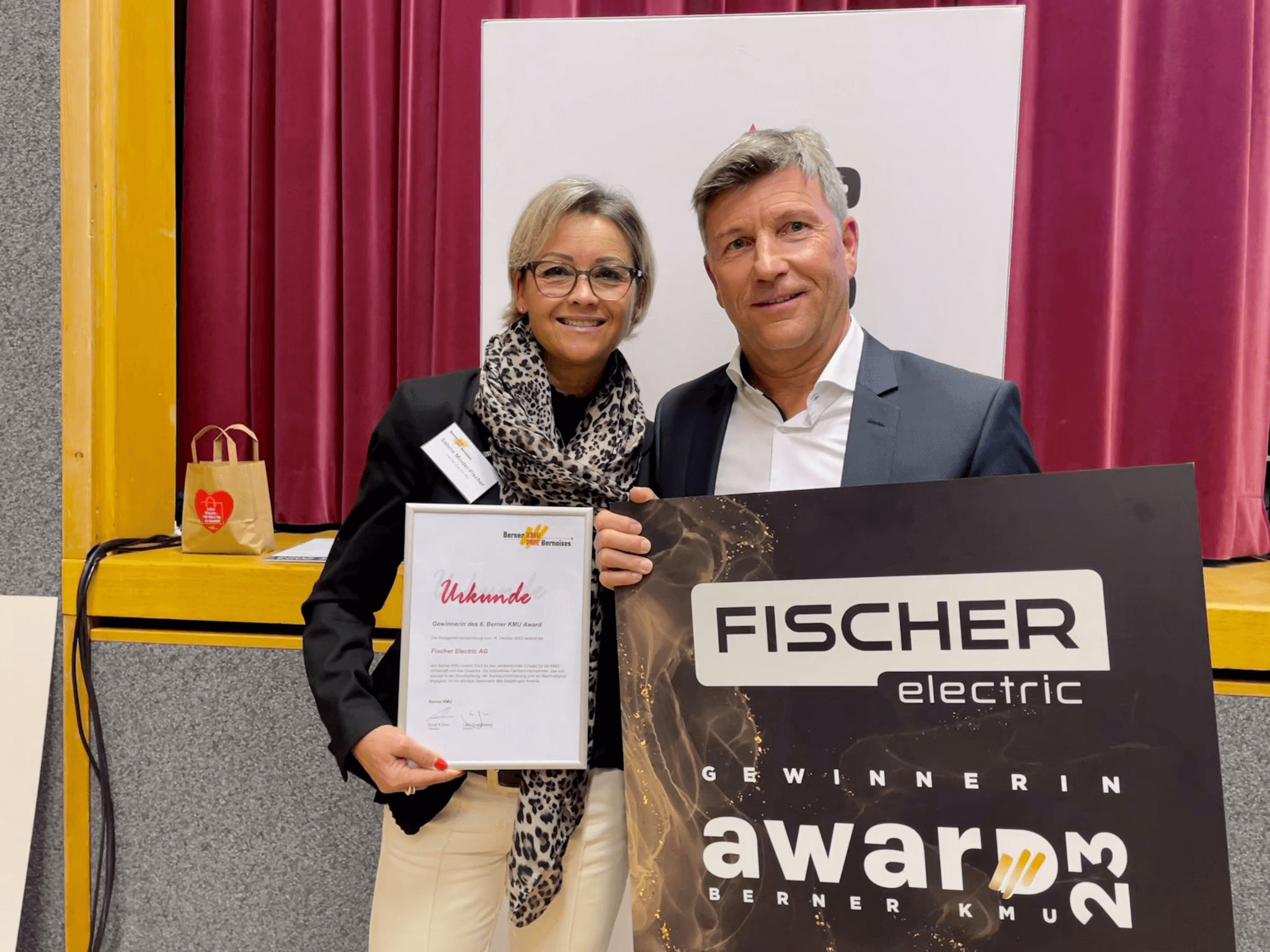 Sabine Minder-Fischer und Hans-Ruedi Minder halten eine Urkunde und eine Gewinner-Tafel des Berner KMU Award