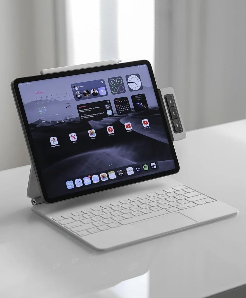 Smiling young man with short hair poses against a dark background, wearing a green button-up shirt.