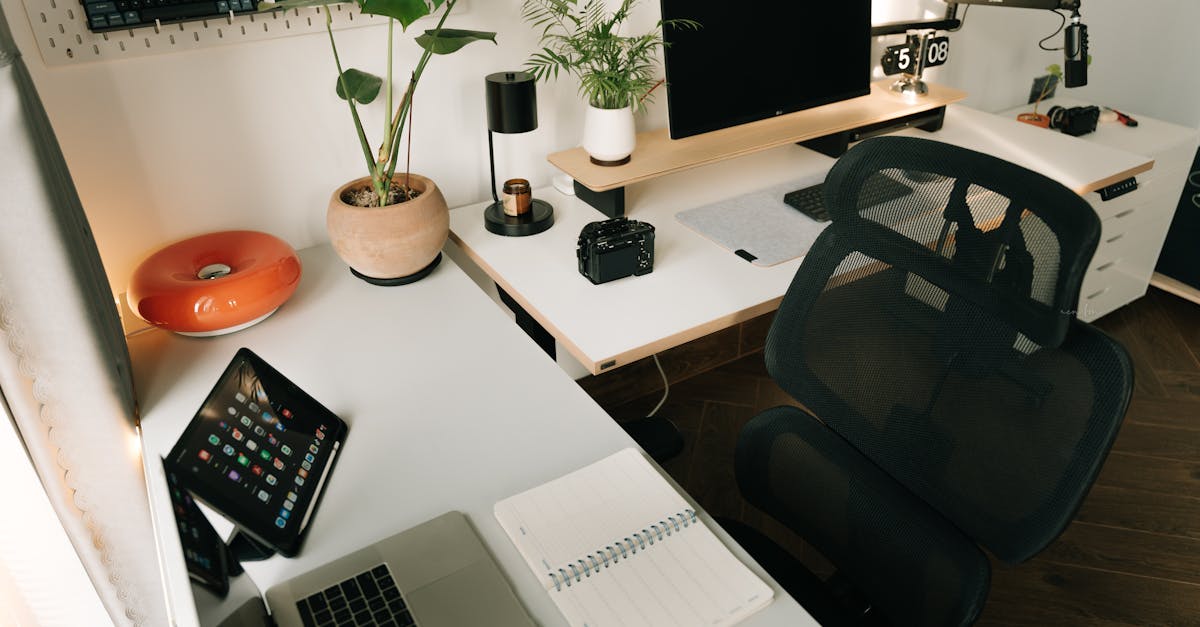A stylish home office setup featuring tech gadgets, a monitor, a tablet, and decorative plants in a
