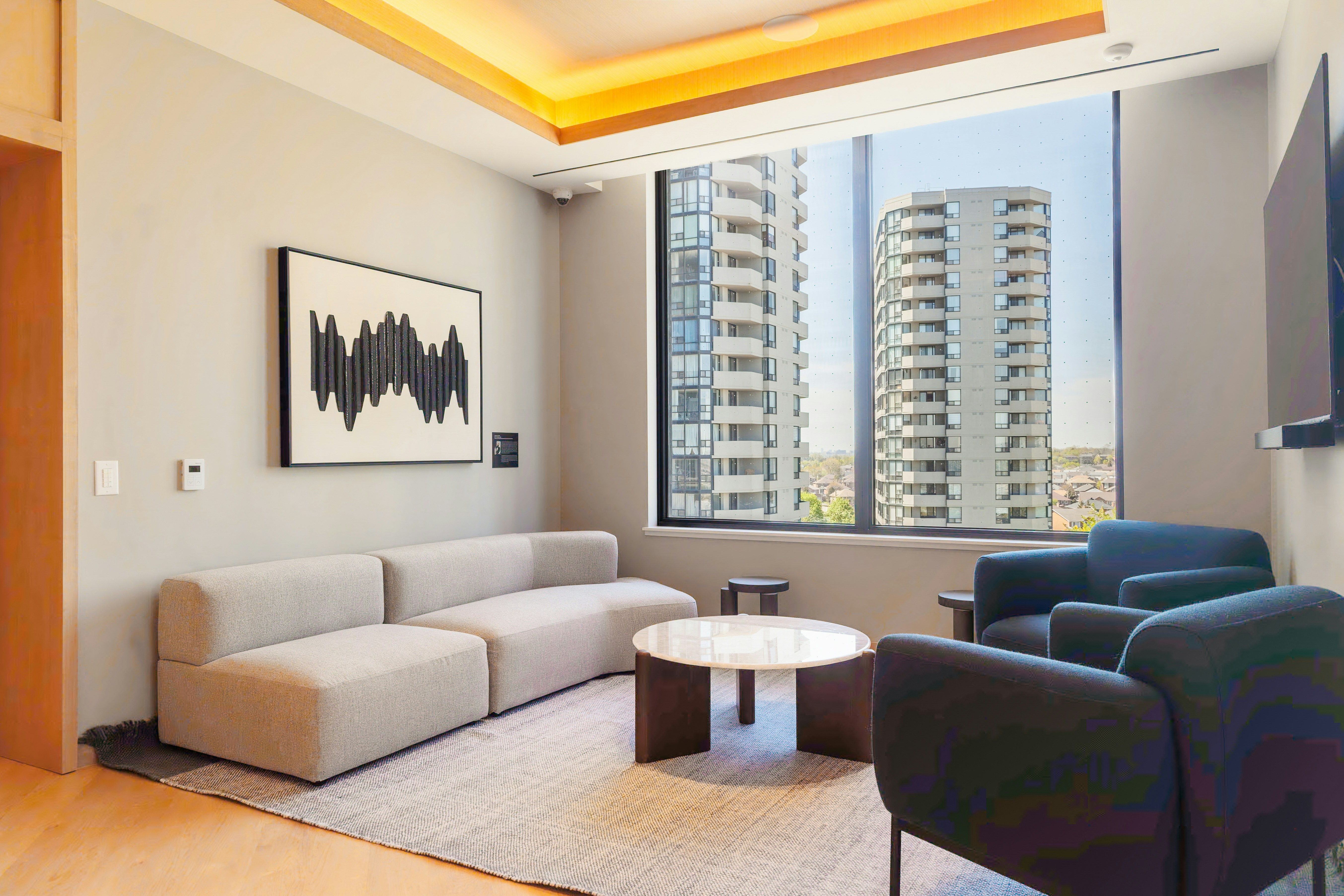 Modern living room with city view and abstract art.