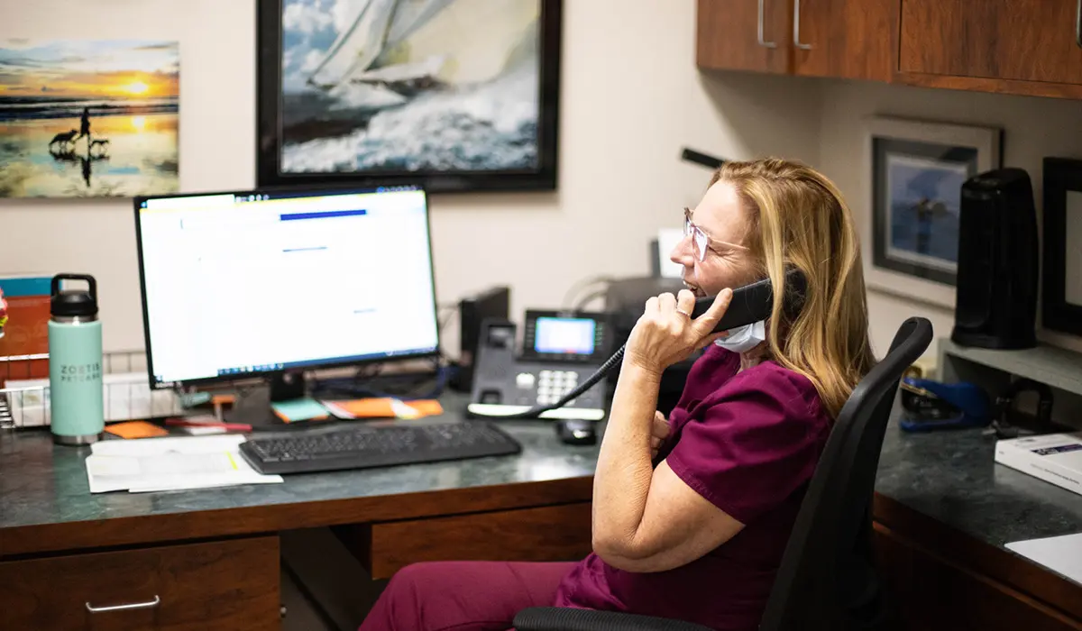 Happy Veterinary CSR chatting on the phone at their desk