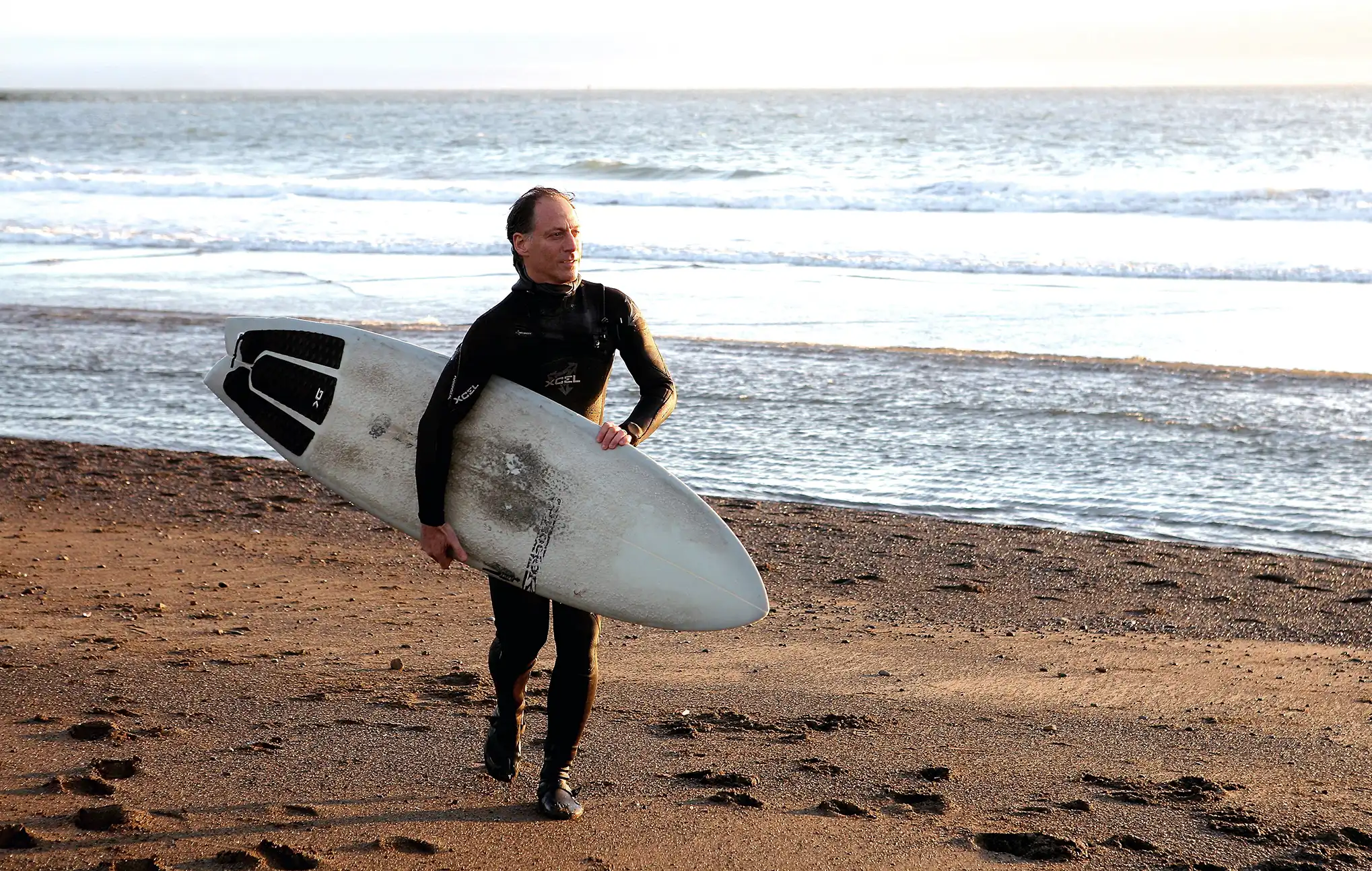 Physician surfing at sunrise, reflecting the connection between movement, recovery, resilience, and long-term health.