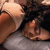 Woman resting in bed to support restorative sleep, cognitive function, recovery, and long-term brain health.