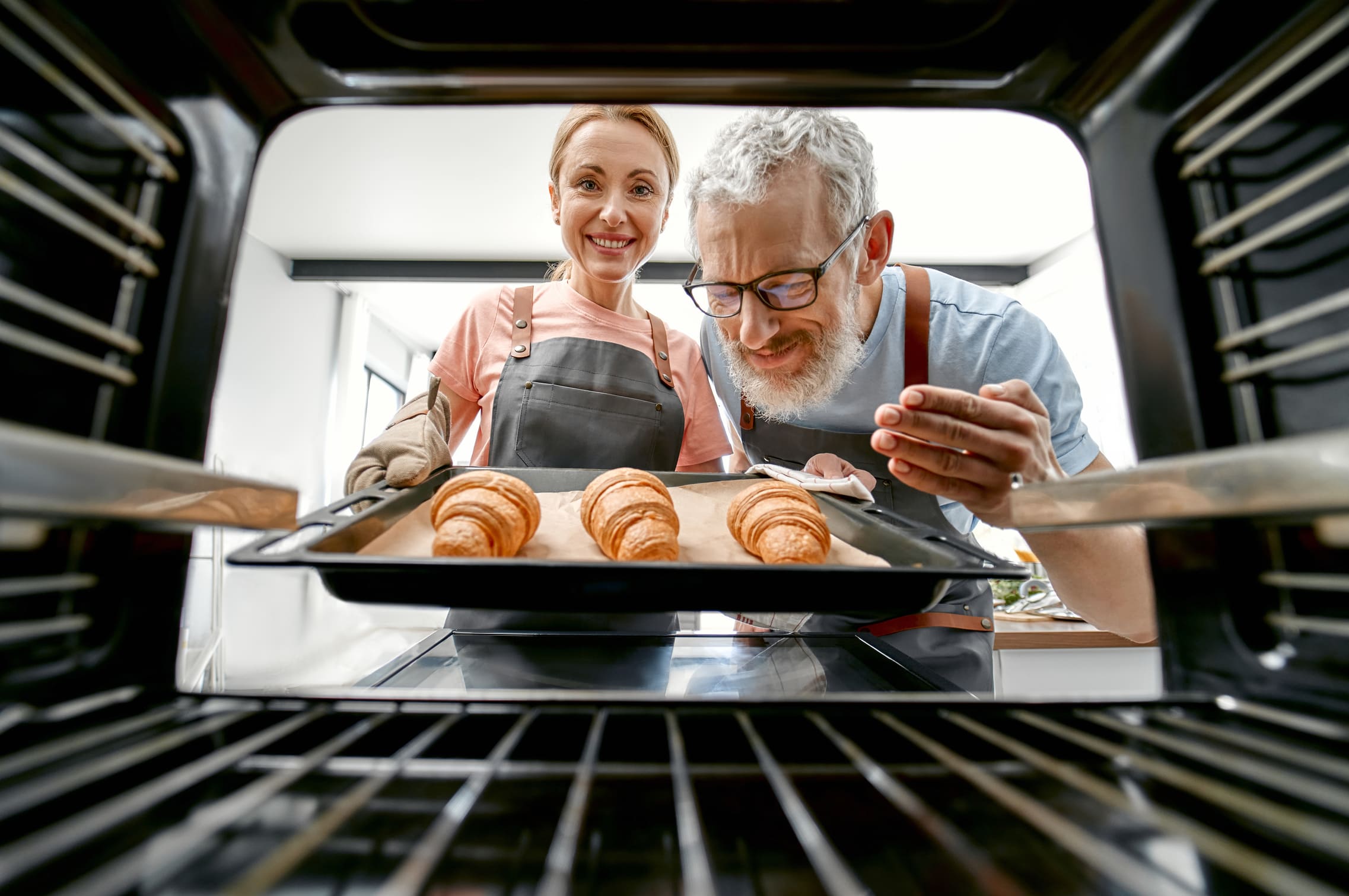 a couple taking out baked goods from the oven