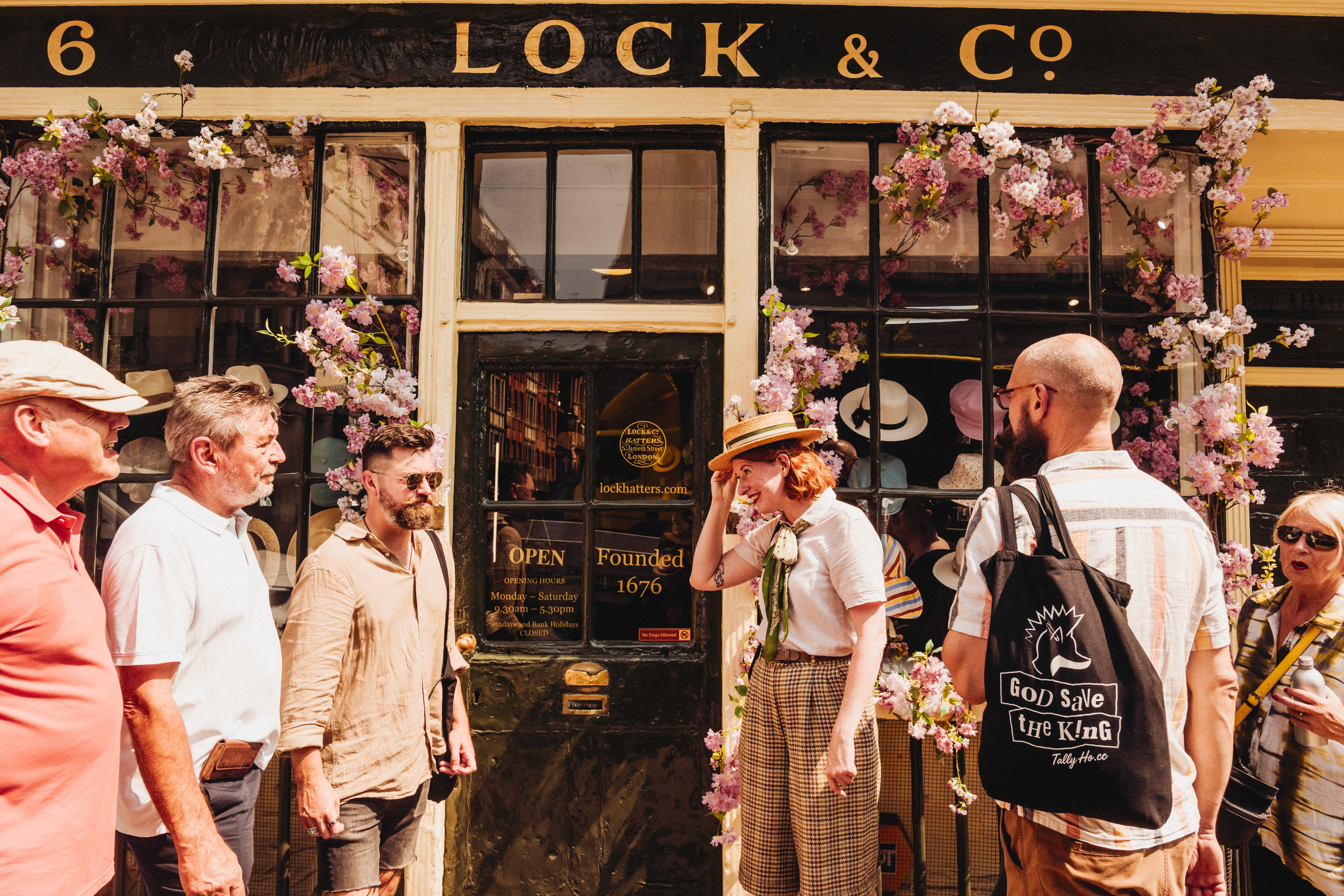 A tour group stops outside of Lock & Co. Hatters 