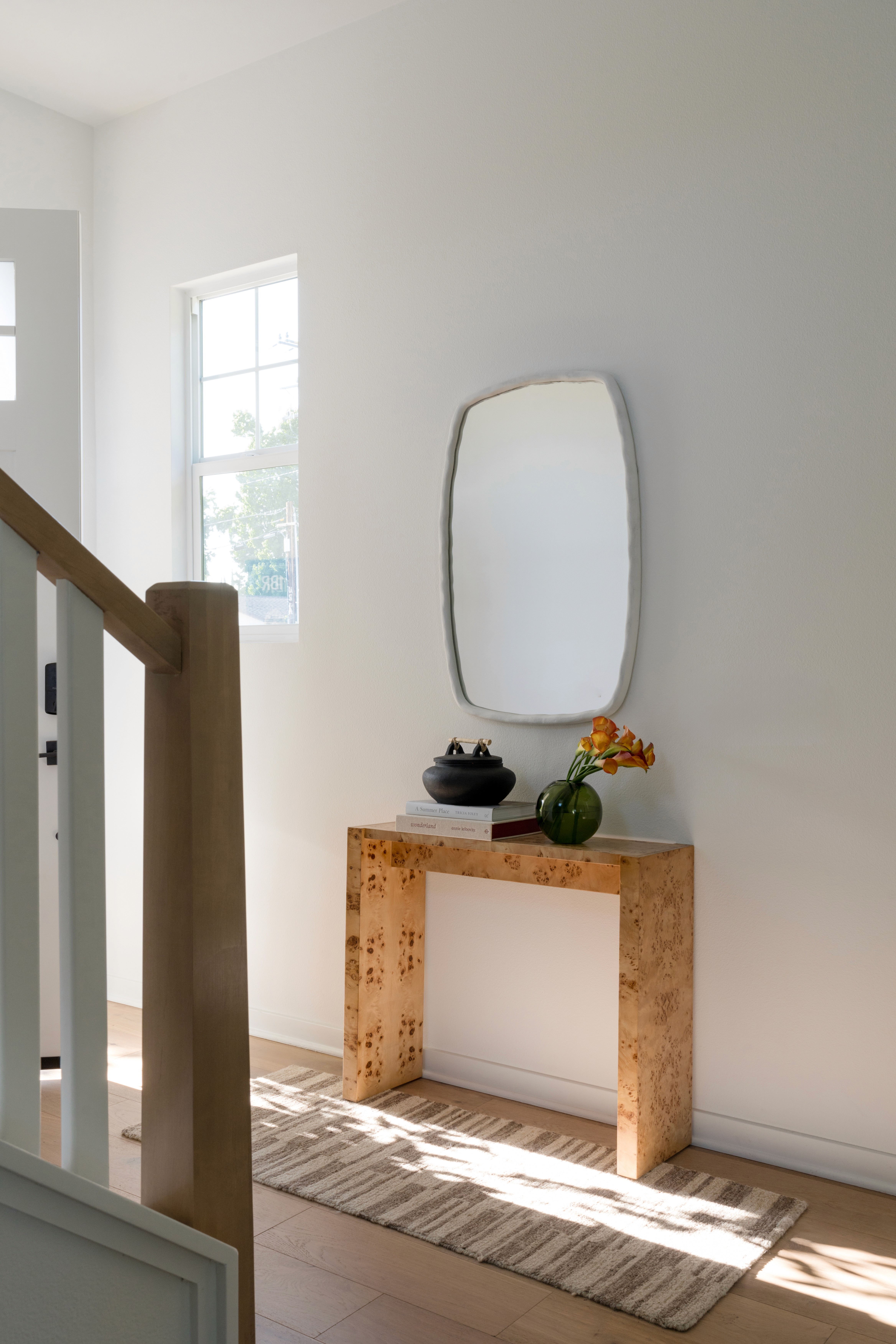 Bright entryway with modern wood console, white framed mirror, and neutral runner by Jubilee Interiors in Arcadia, California