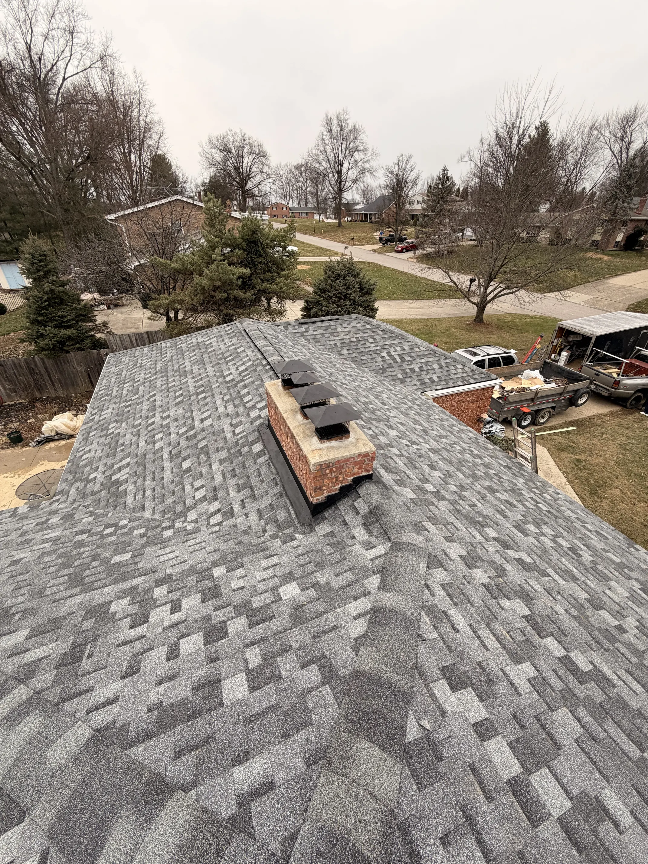 Basement bar remodel in Northern Kentucky by Thelen Estates featuring a modern marble island, wood accents, sleek black cabinetry, and open liquor shelving.