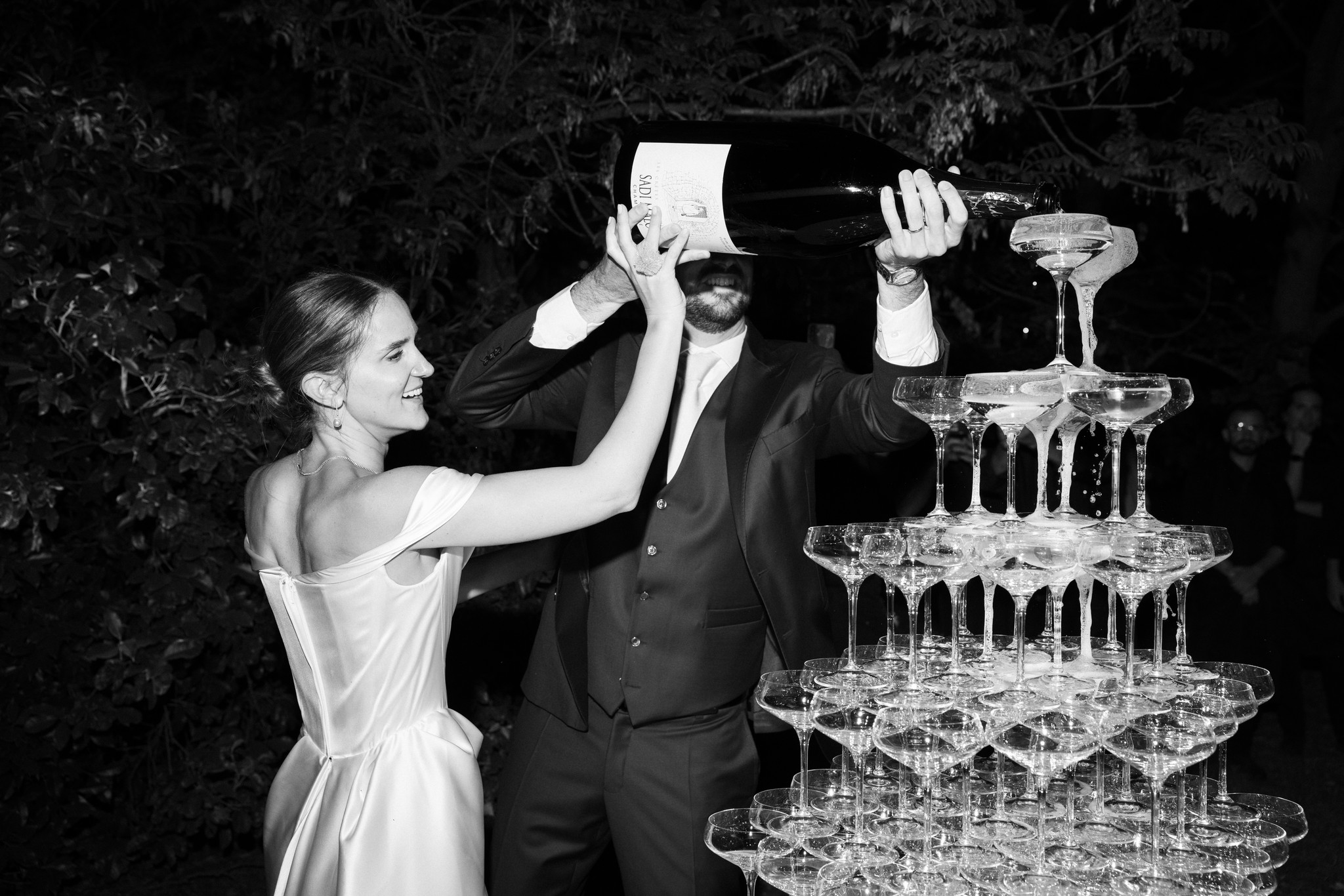 Sposi brindano con champagne tower al Castello di Scipione, momento festivo in bianco e nero durante il ricevimento di nozze