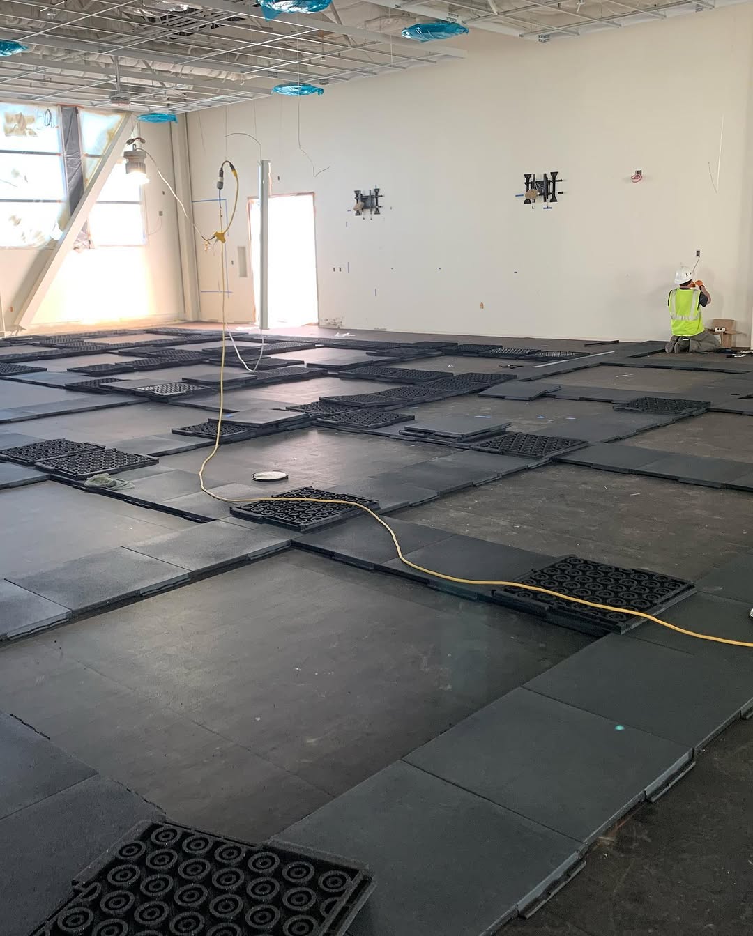 Dark rubber tiles being set over an acoustic isolation mat