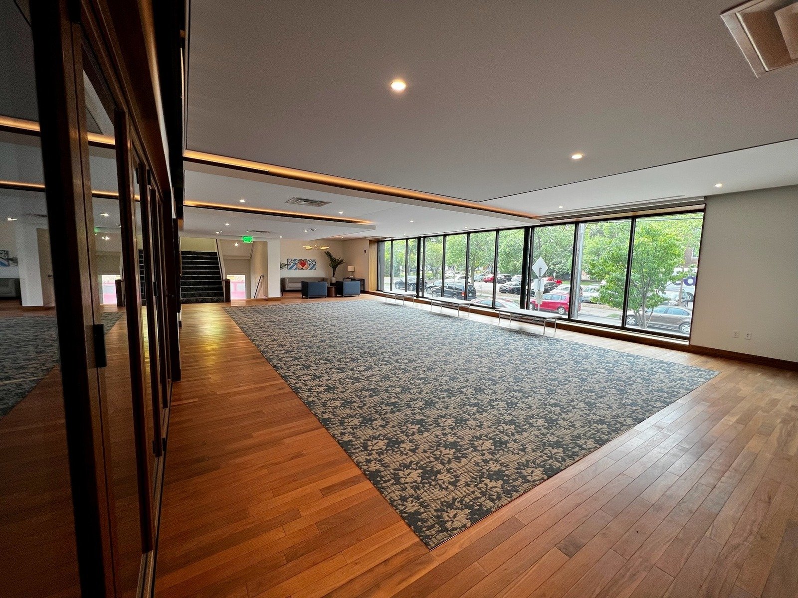 Spacious room with large windows and natural light, featuring hardwood floors, patterned carpet, and seating area, available for rent at Grace Trinity Church