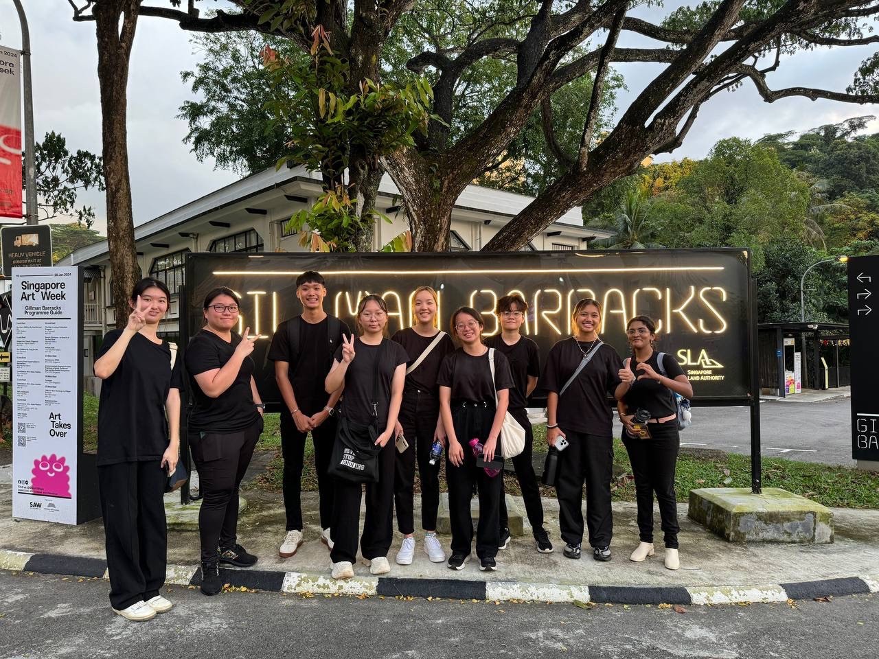 A wooden desk by a window, with sunlight illuminating a laptop, notebook, and a decorative vase.