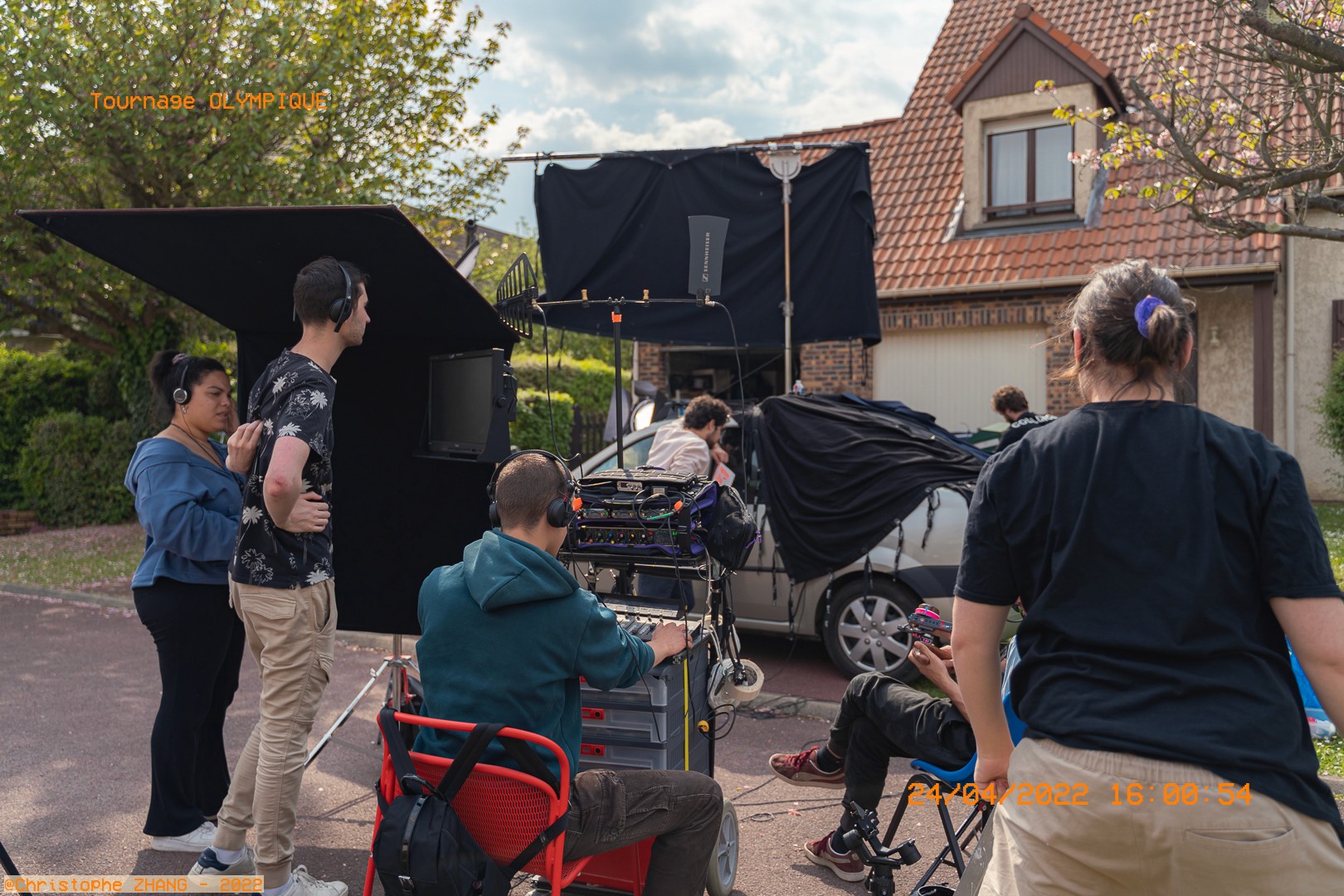 Tournage en extérieur devant une maison, le réalisateur et l'équipe technique concentrés