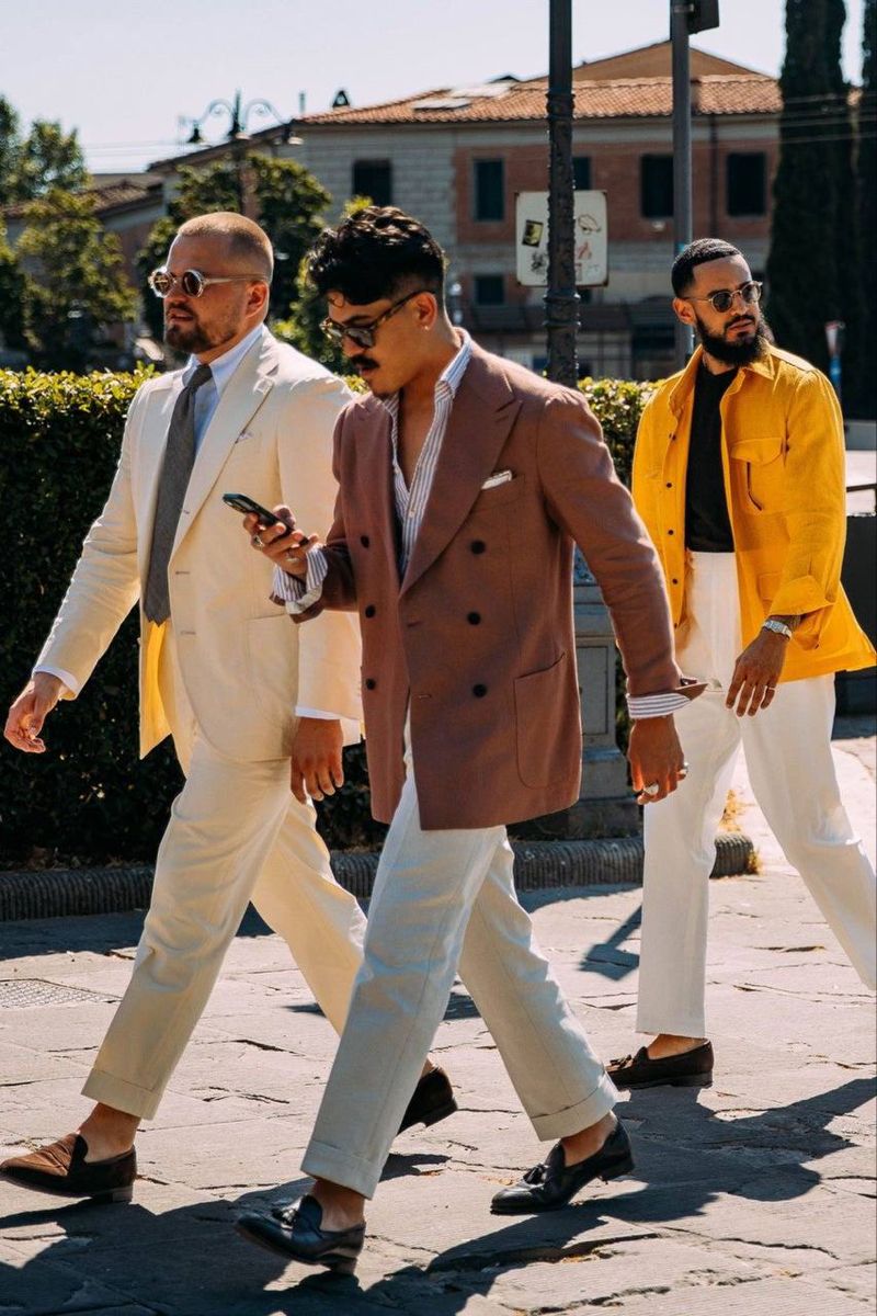 Group of hikers walking through a mountain meadow surrounded by pine trees and misty peaks.