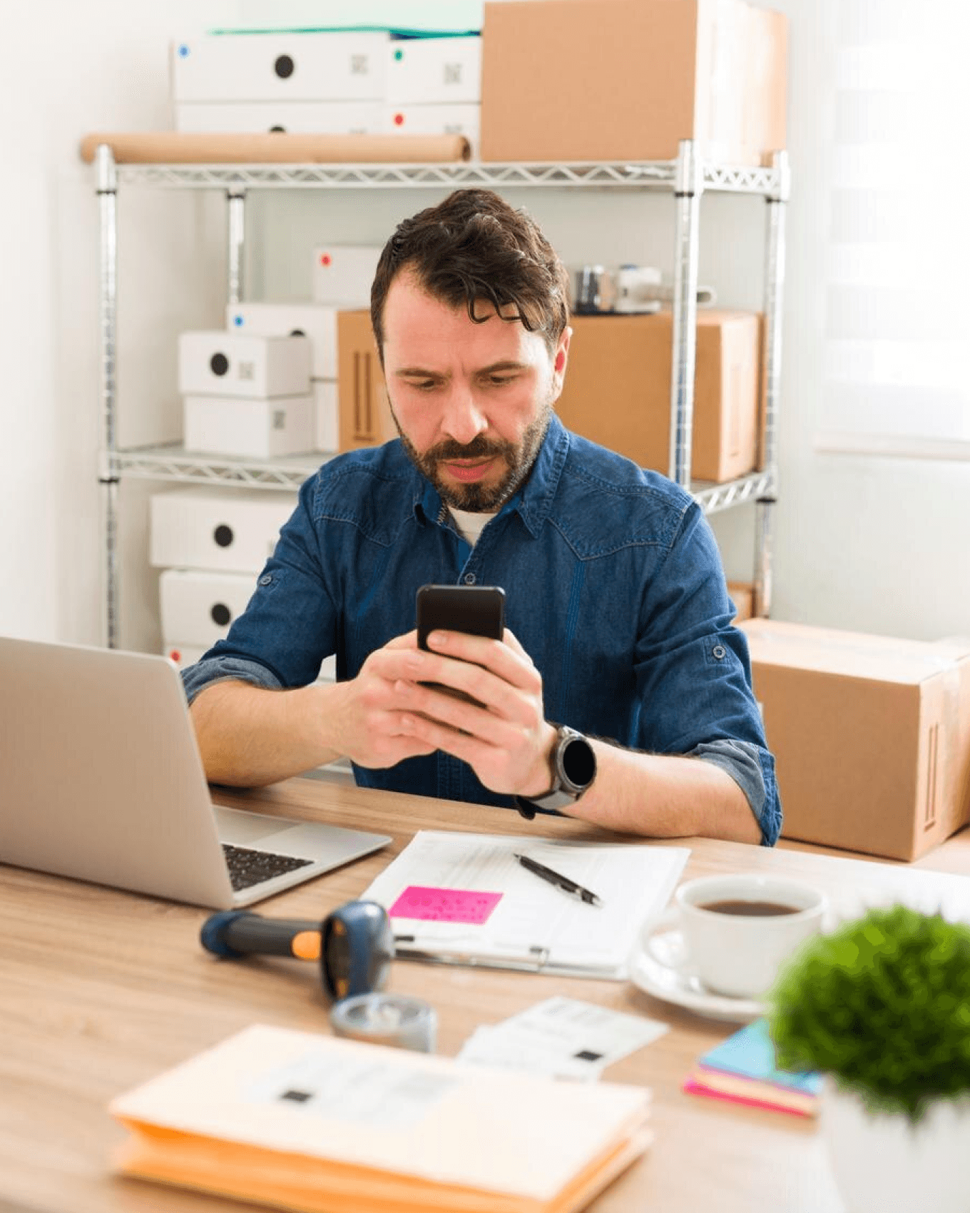 A man using a phone while sitting in a warehouse or backyard-like environment