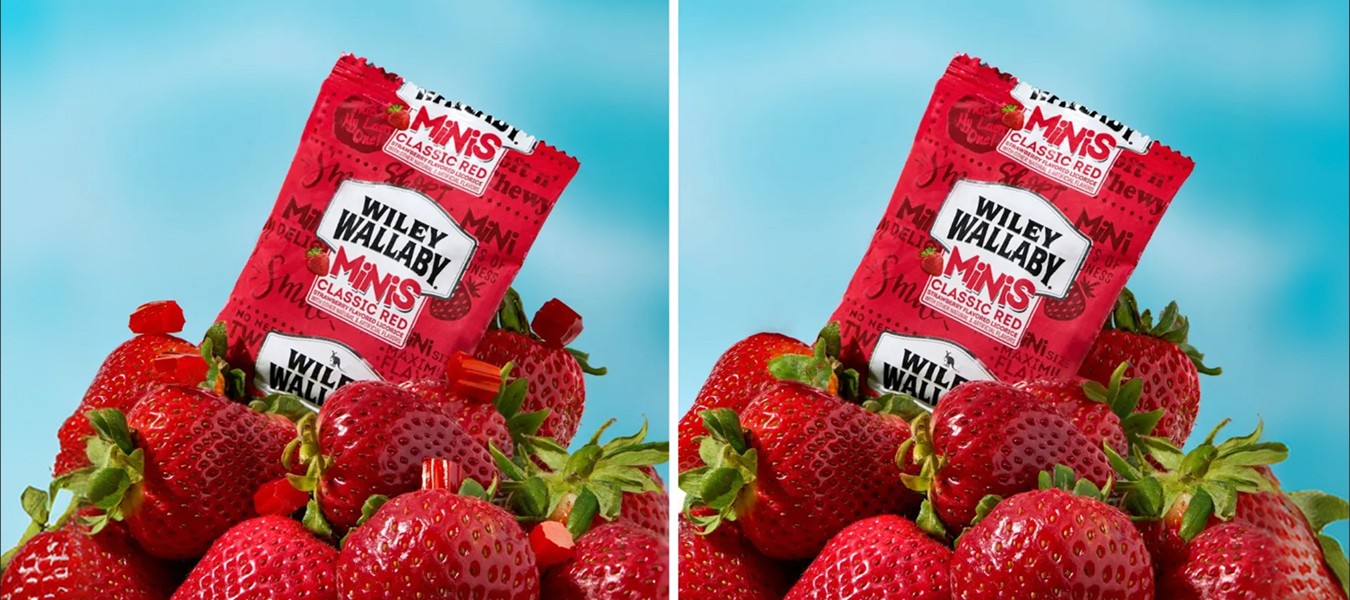 Wiley Wallaby Classic Red Minis candy pouch styled on fresh strawberries against a blue background